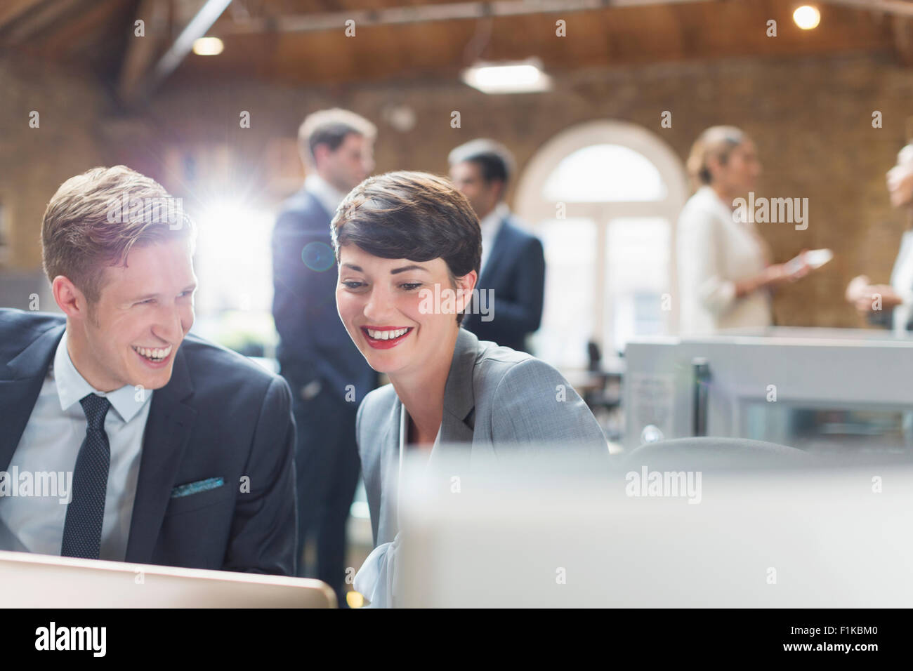 Sorridente business persone che lavorano al computer portatile in ufficio Foto Stock