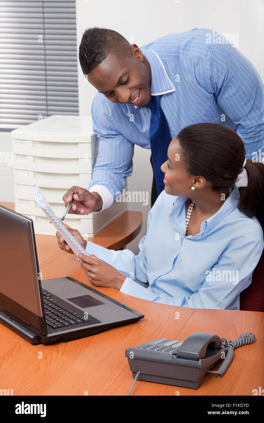 Un imprenditore aiutando il suo dipendente alla sua scrivania Foto Stock