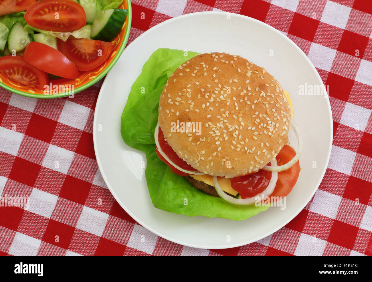 Cheeseburger con insalata verde shot dalla sommità di rosso e bianco di panno a scacchi Foto Stock