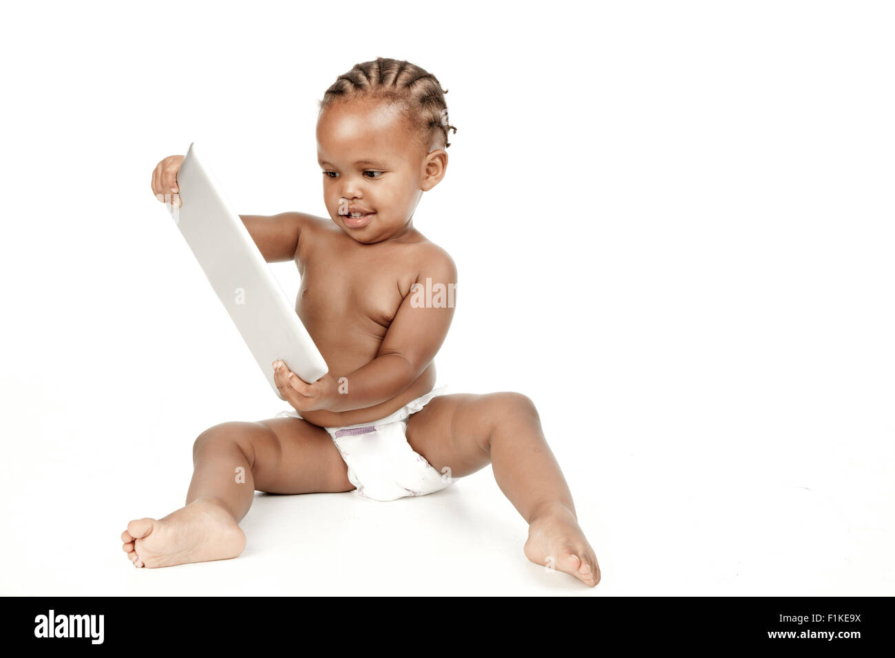 Un bambino si siede di fronte a uno sfondo bianco, a giocare con un PC tablet Foto Stock