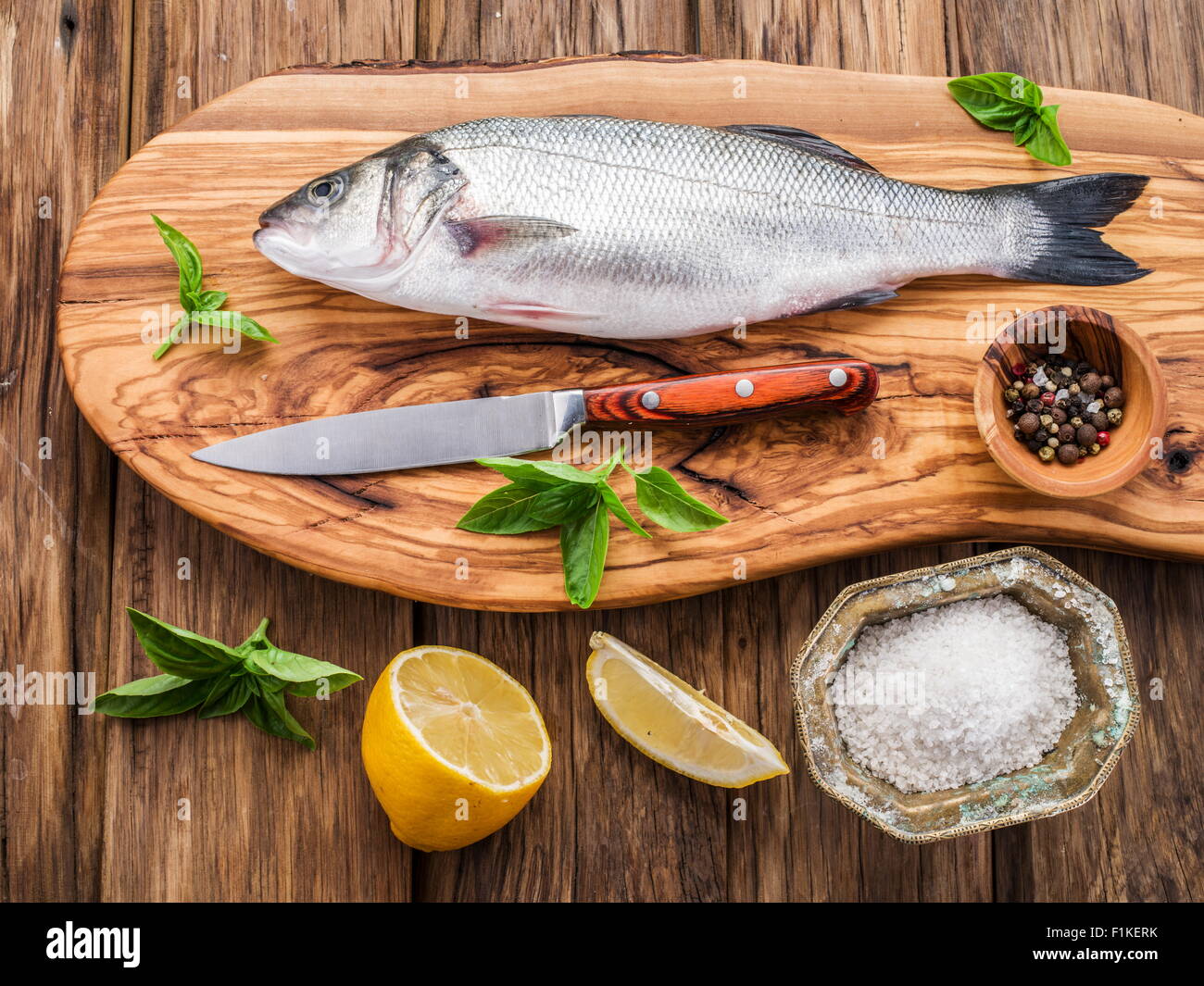 Spigola pesce sul tagliere di legno. Foto Stock