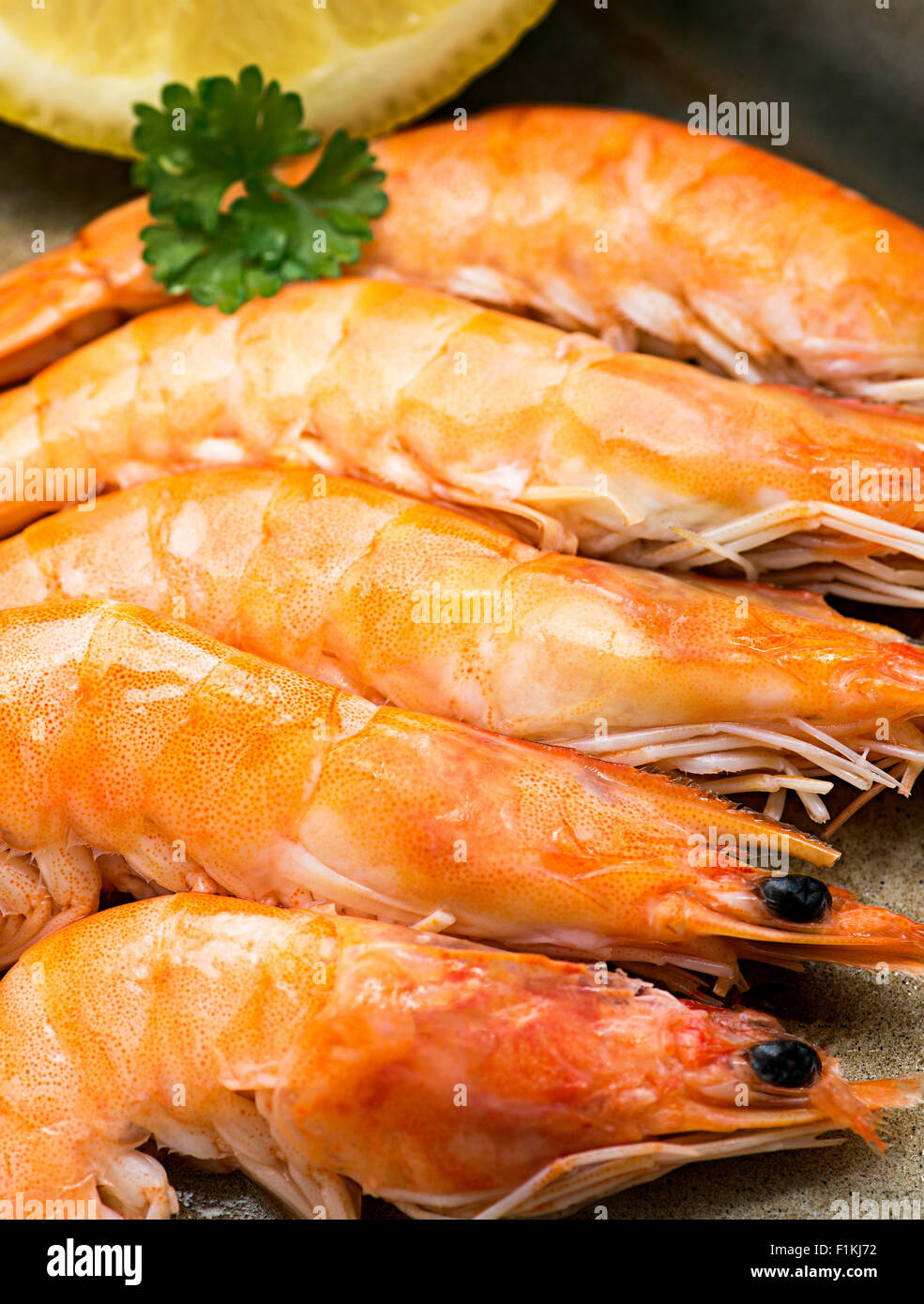 Gamberi preparati in un vassoio con limone e prezzemolo una immagine verticale con una piccola profondità di campo e la messa a fuoco in corrispondenza del fondo. Foto Stock