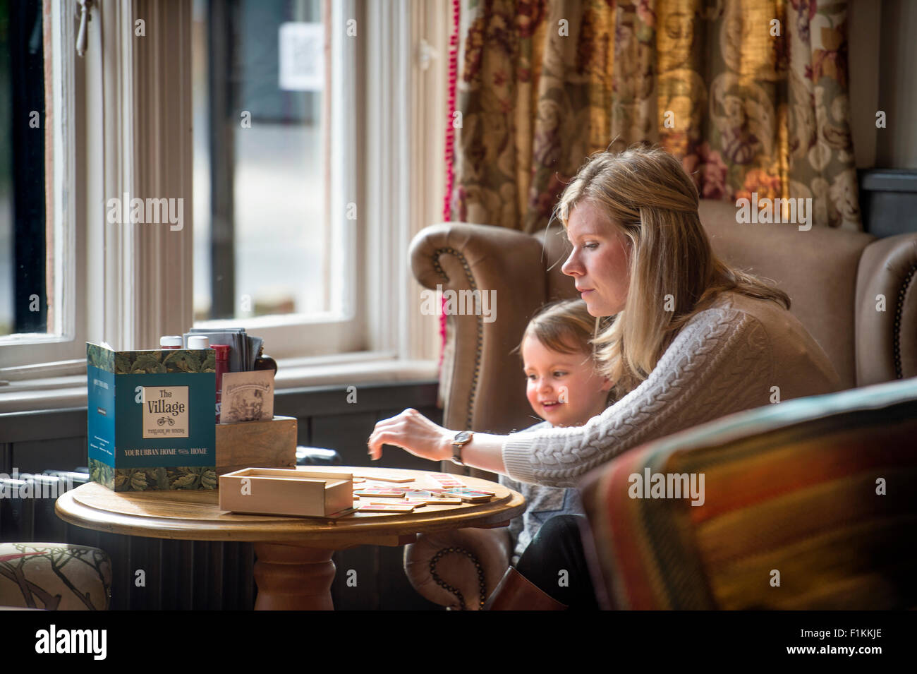 Una madre gioca un gioco con la figlia in un pub UK Foto Stock