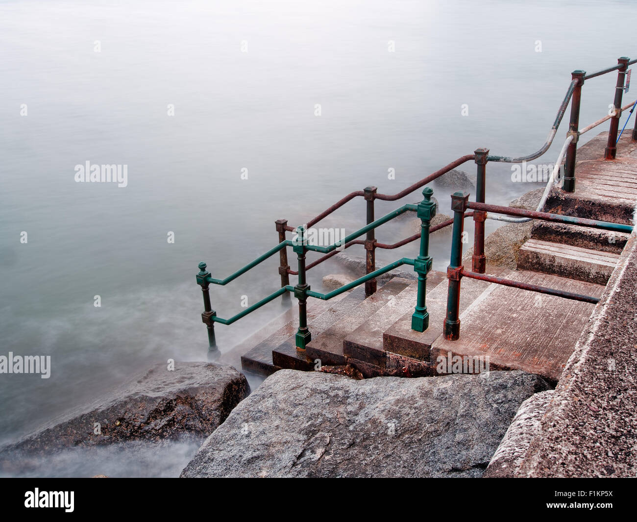 Le scale conducono al freddo grigio mare. Foto Stock