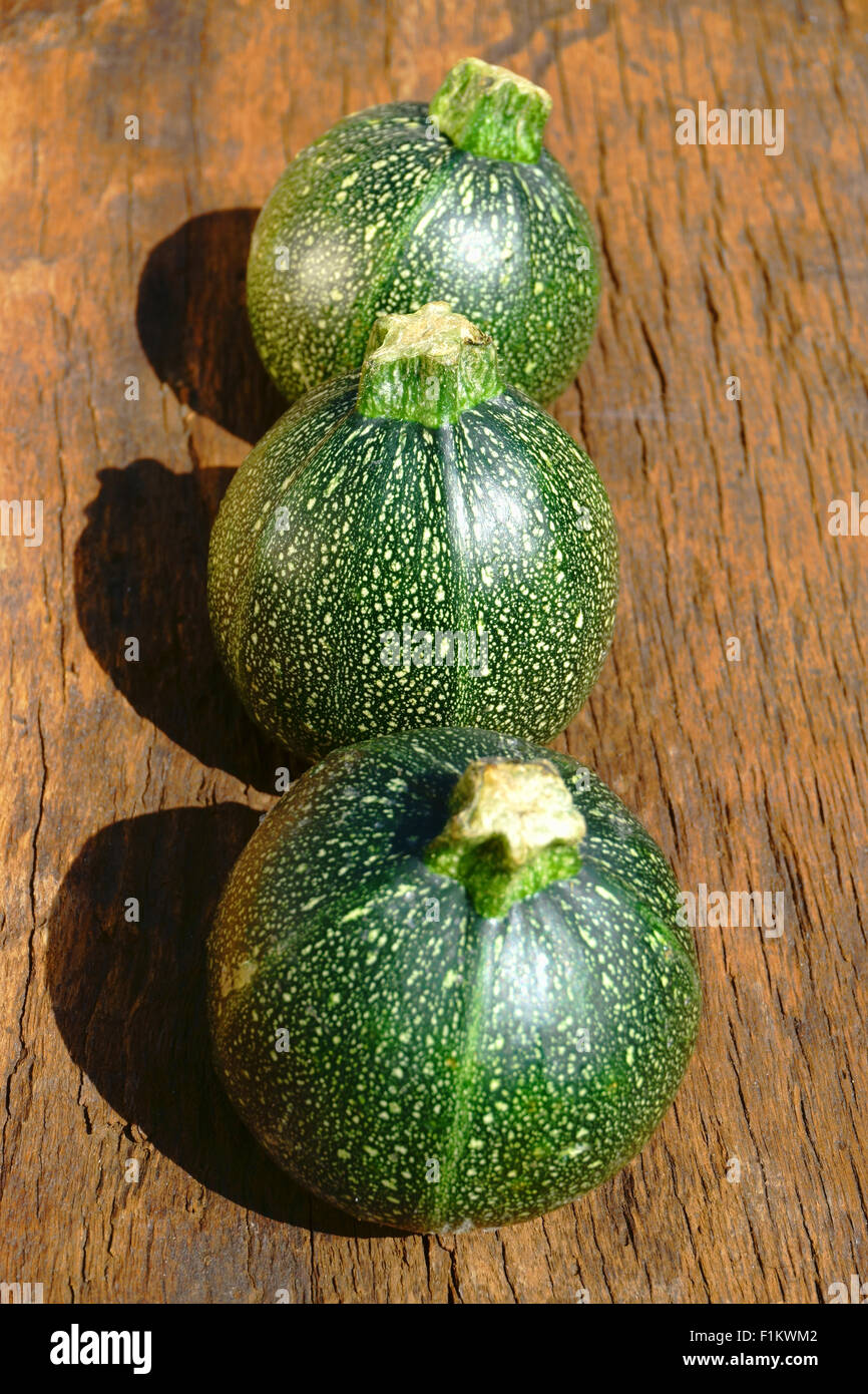 Tre round e mature Zucchine dietro l'altra su rustiche tagliere di legno Foto Stock