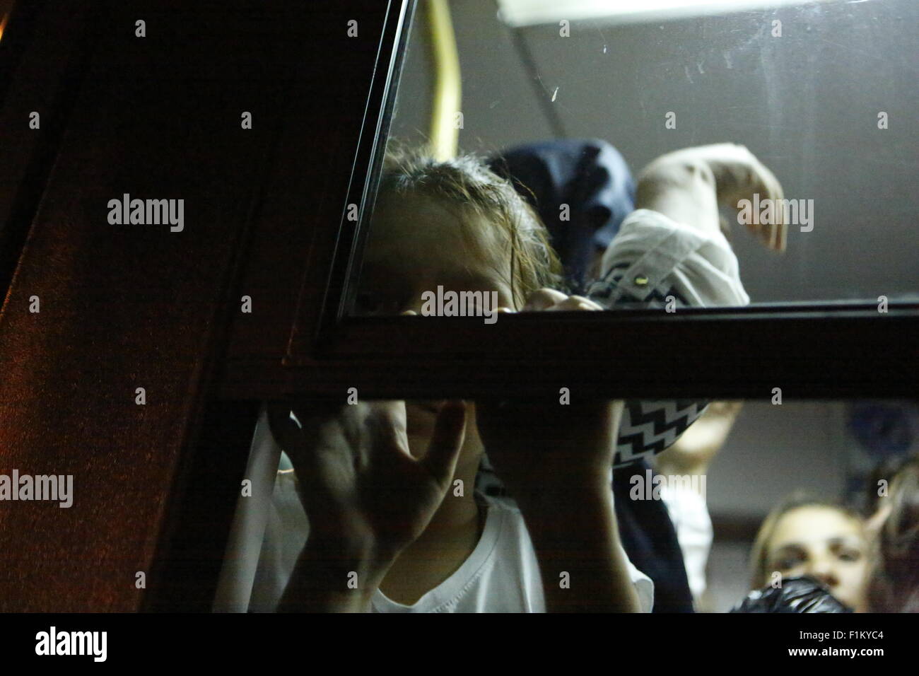 Atene, Grecia. Il 3 settembre 2015. Una bambina guarda fuori dalla finestra del bus che la porterà alla stazione ferroviaria di Pireo. Migliaia di rifugiati sono arrivati nel porto del Pireo a bordo il governo chartered Tera Jet traghetto dall'isola greca di Lesbo. Centinaia e centinaia di rifugiati, per la maggior parte dalla Siria e Afghanistan arrivare sulle isole greche ogni settimana, aggiungendo alla già numero di migliaia di profughi già sulle isole greche. Credito: Michael Debets/Alamy Live News Foto Stock