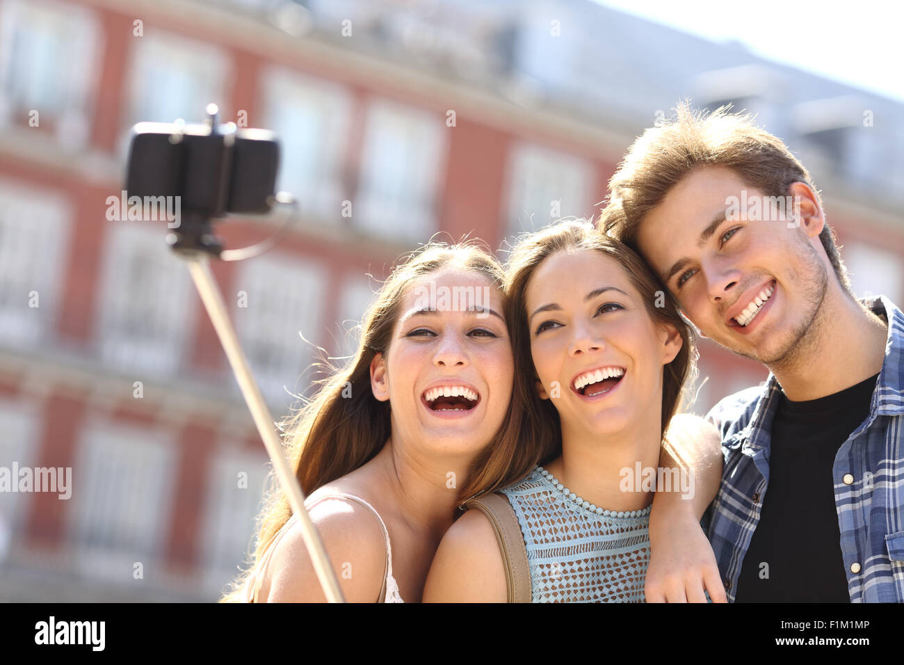 Gruppo di tre amici turistica prendendo selfie con smart phone tenere in mano monopiede in strada Foto Stock