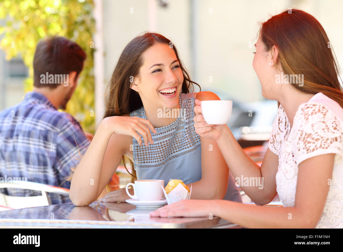 Due amici o sorelle di parlare tenendo una conversazione in una caffetteria terrazza guardando ogni altro Foto Stock