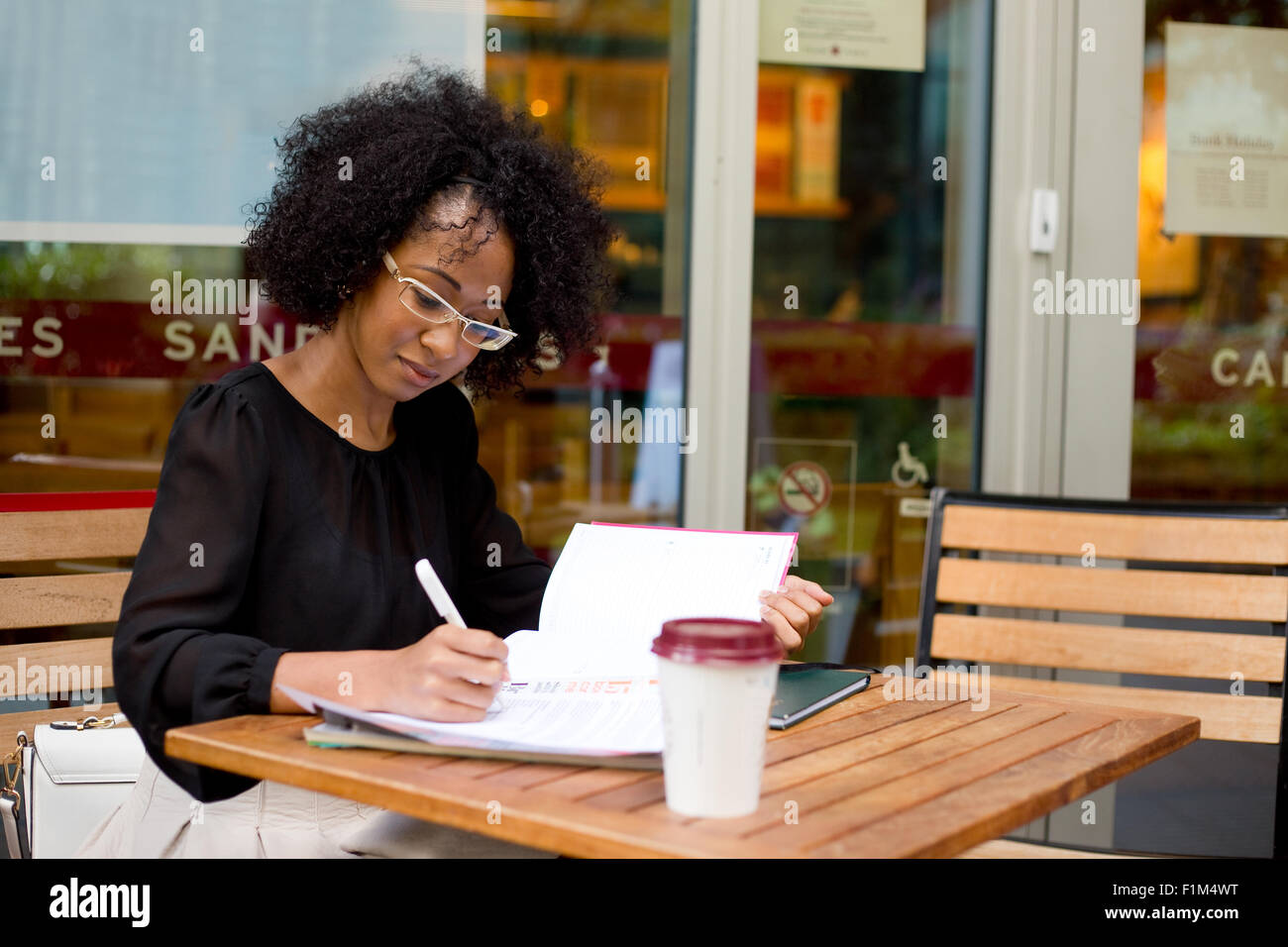 Giovane donna a un coffee shop iscritto nel suo diario Foto Stock