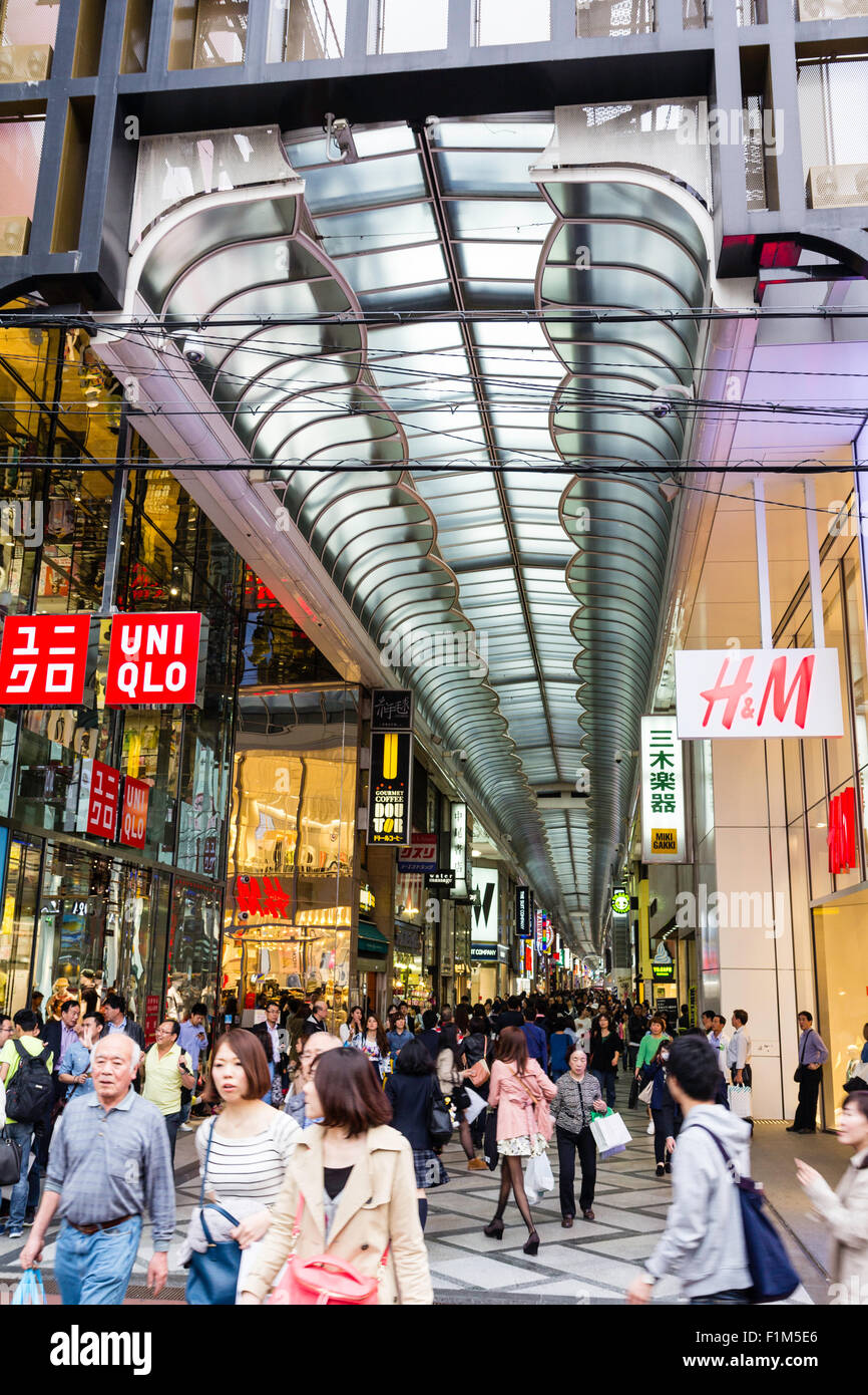 Giappone, Osaka. Guardando lungo Shin Saibashi Suji coperto shopping street, H&M e Uni Qio negozi in primo piano Foto Stock
