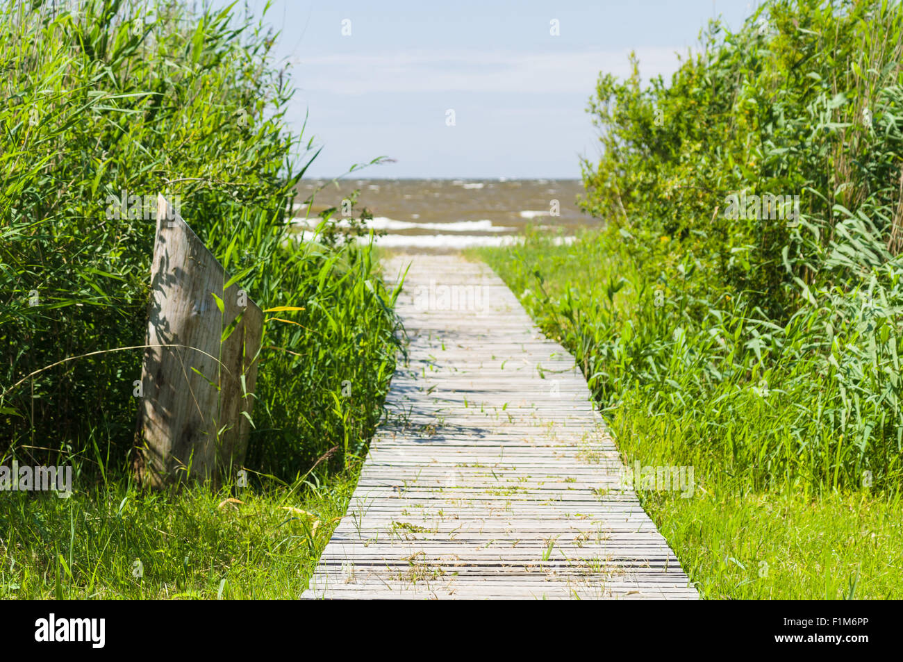 Passerella in legno che conduce ad un mare costa, immagine sfocata Foto Stock