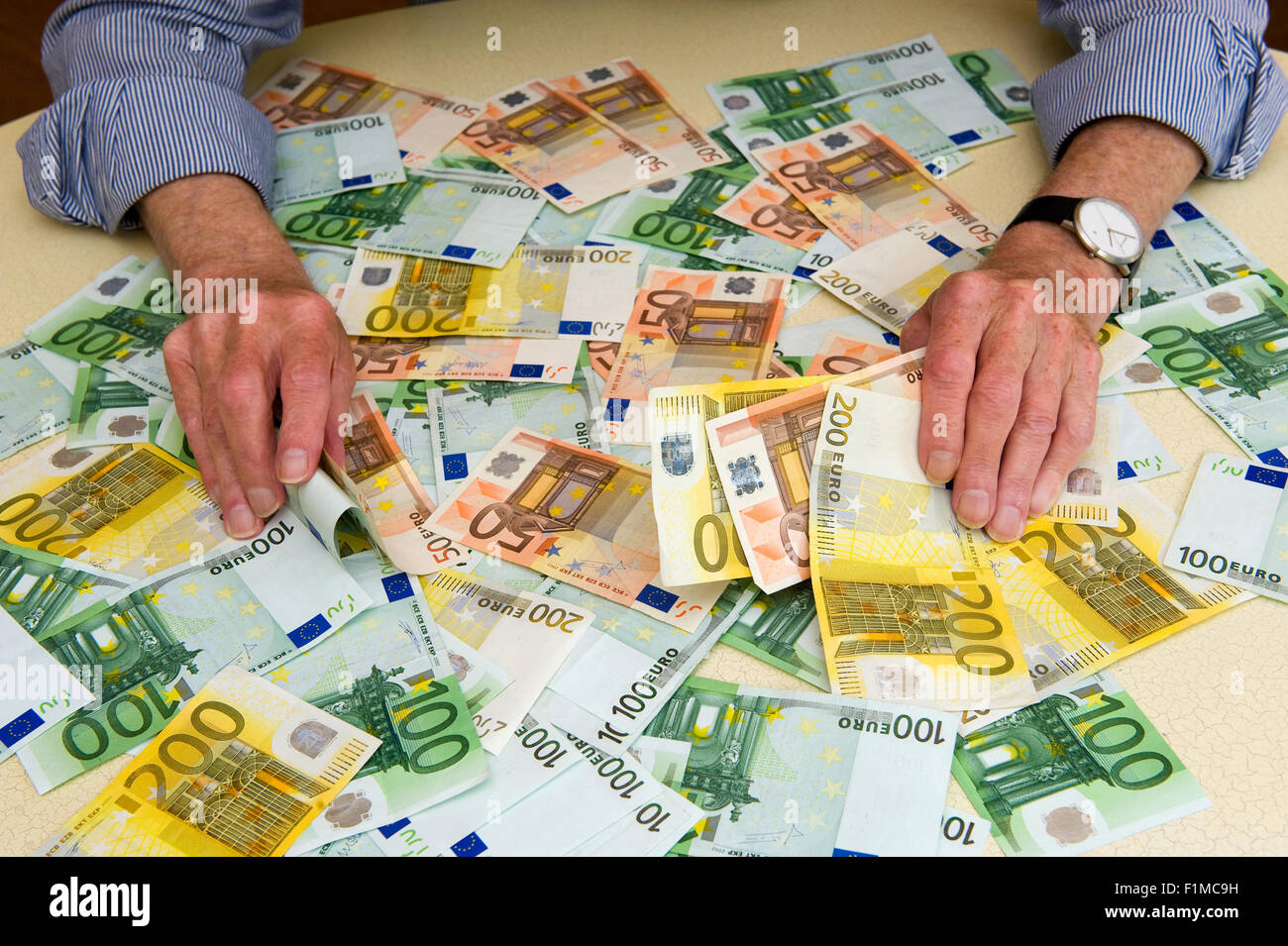 Un uomo anziano con un sacco di banconote in euro sul tavolo Foto Stock
