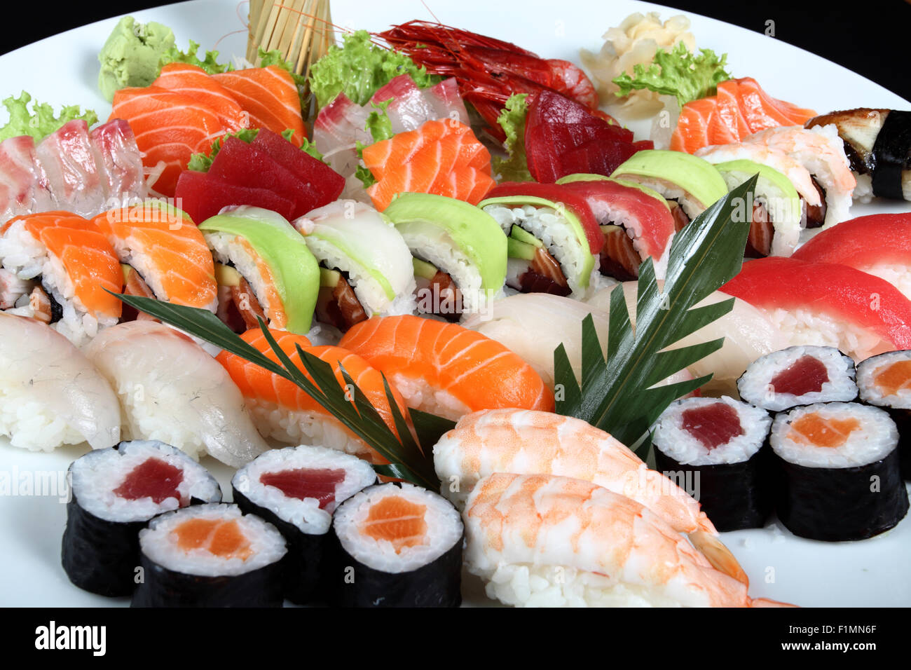Close-up sushi e sashimi misti su round piastra bianca su sfondo nero Foto Stock
