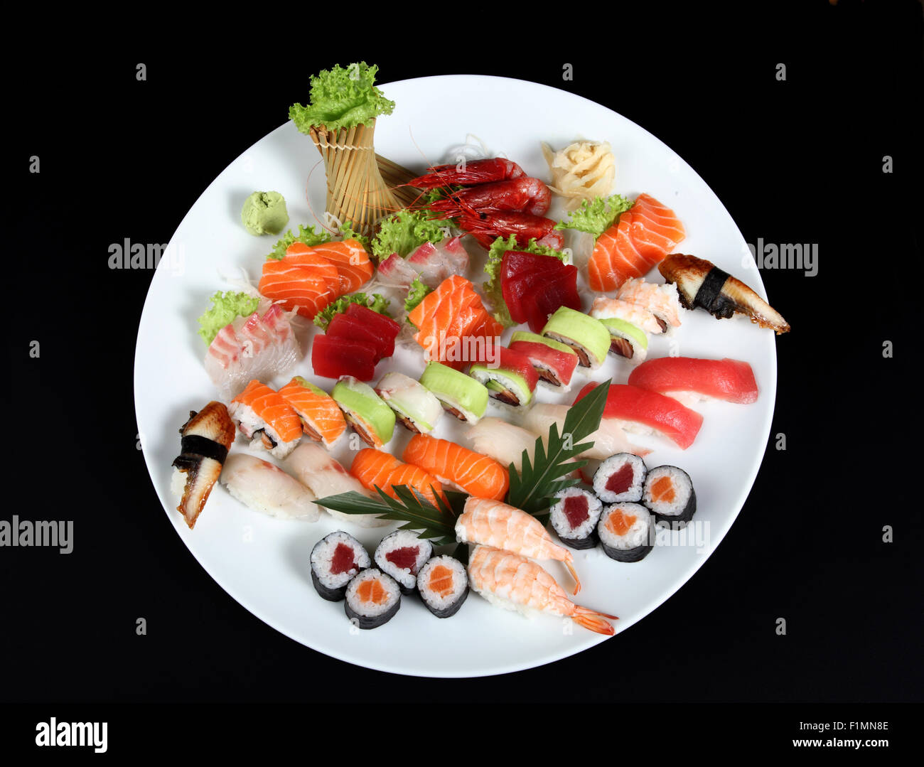 Il sushi e il sashimi miscelati sul round piastra bianca su sfondo nero Foto Stock