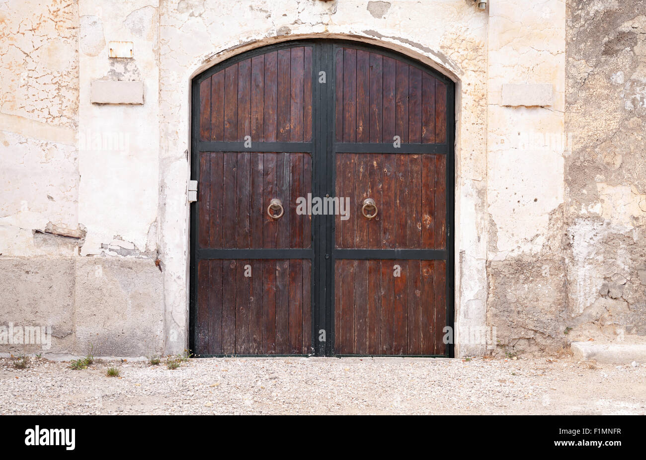 Antica porta in legno con arco in pietra a parete, texture di sfondo Foto Stock