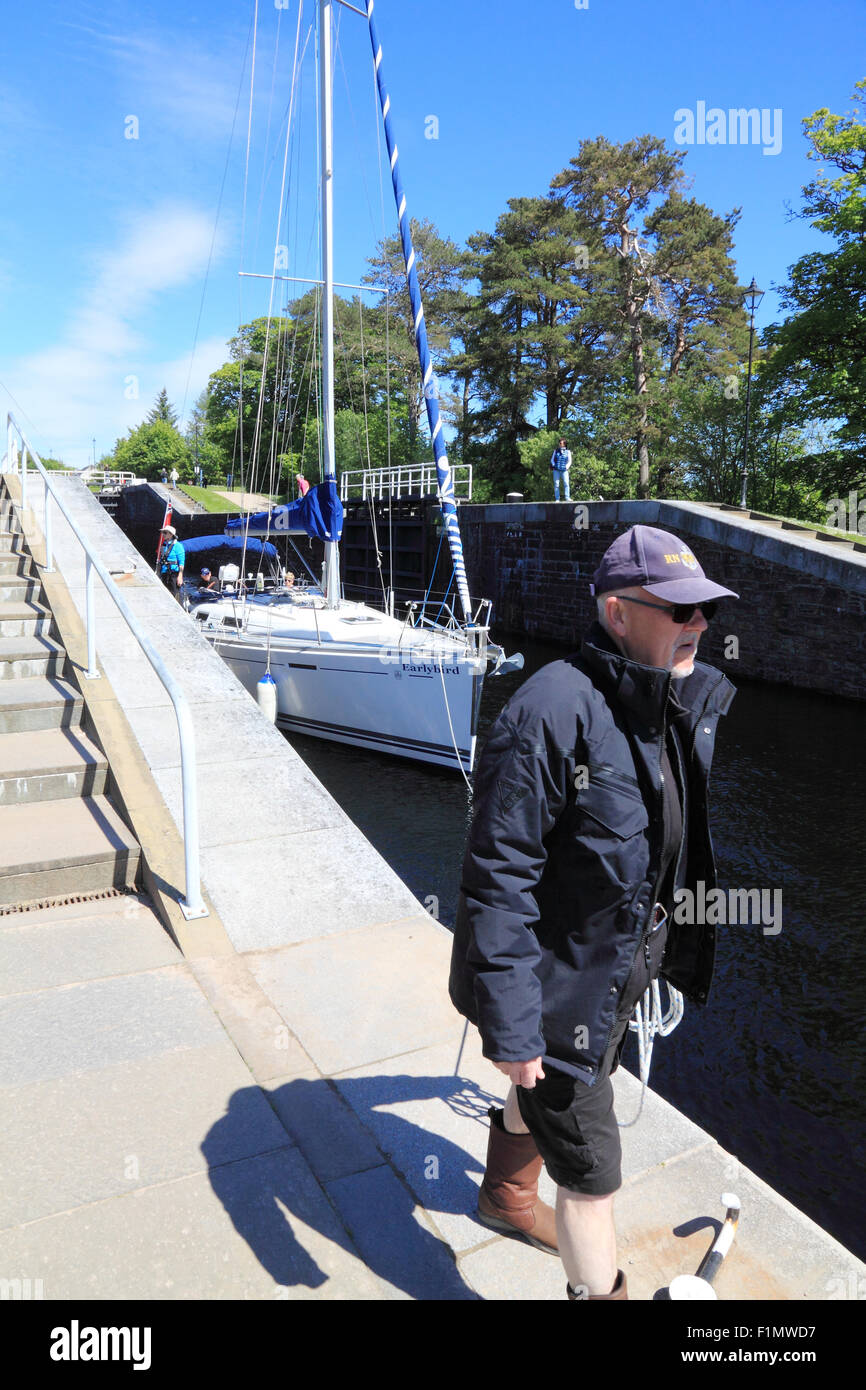 Un marinaio guide una barca per il tempo libero attraverso le chiuse di Nettuno, scala su Caledonian Canal, Scozia. Foto Stock
