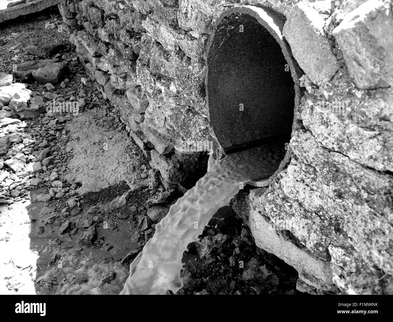 Visualizzazione monocromatica dell'acqua fluisce da un arrugginito canalizzazioni fognanti Foto Stock