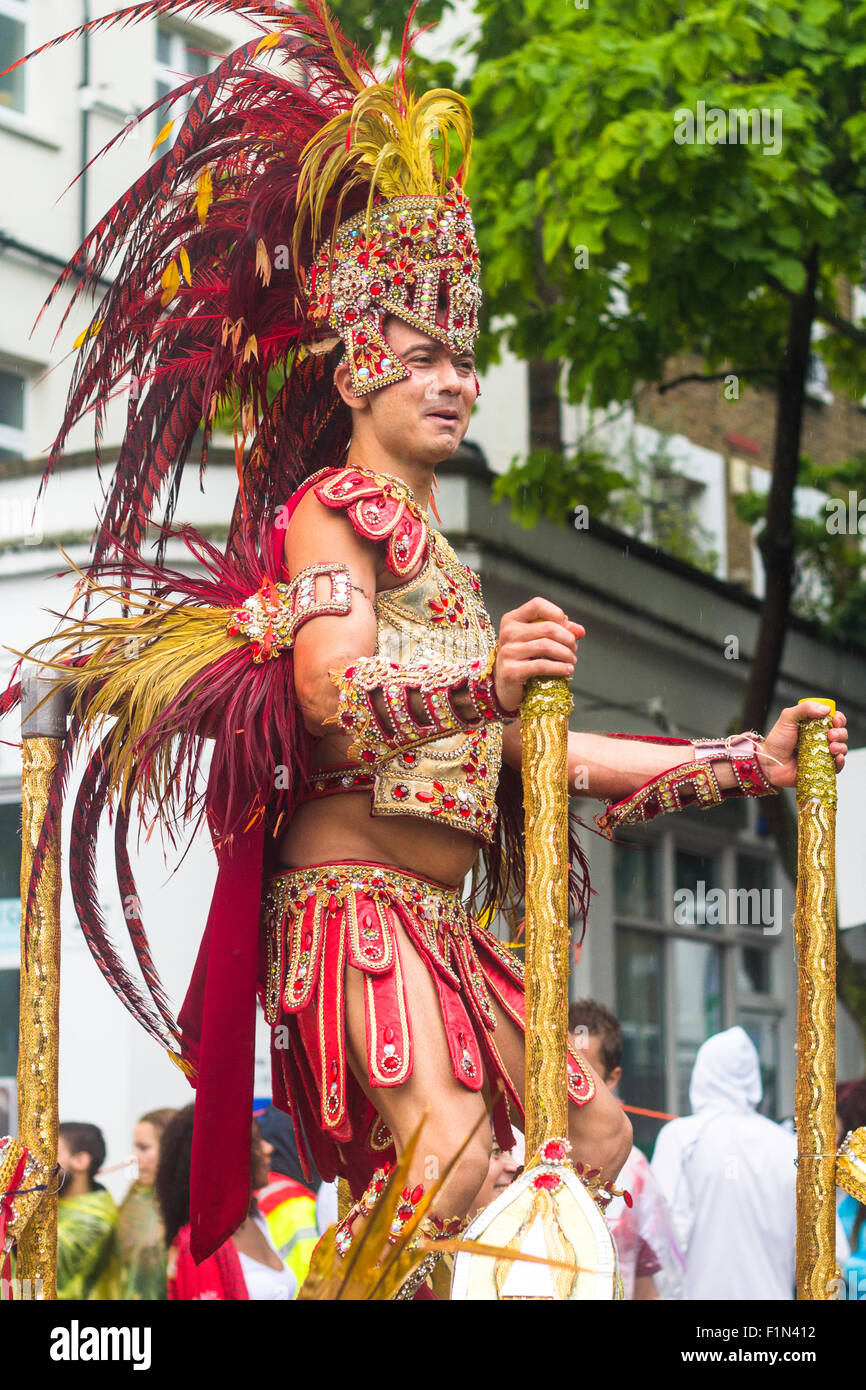 Un ballerino maschio indossando vestiti esotici in piedi sul galleggiante e ballare come la parata passa attraverso Notting Hill e Ladbroke Grove Foto Stock