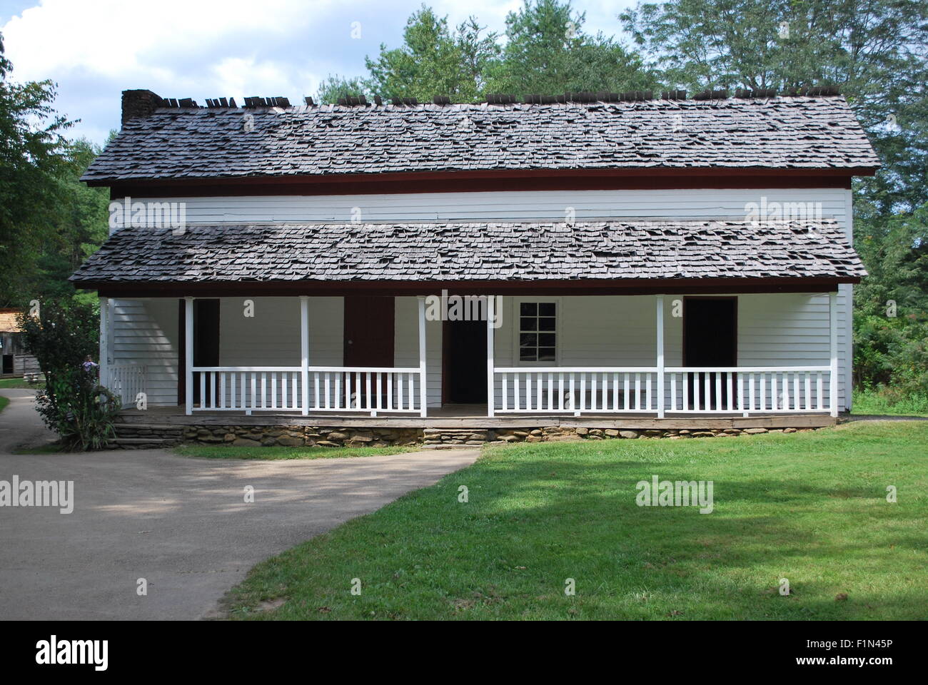 Un bianco country house con alberi di pino e cielo blu sullo sfondo. Foto Stock