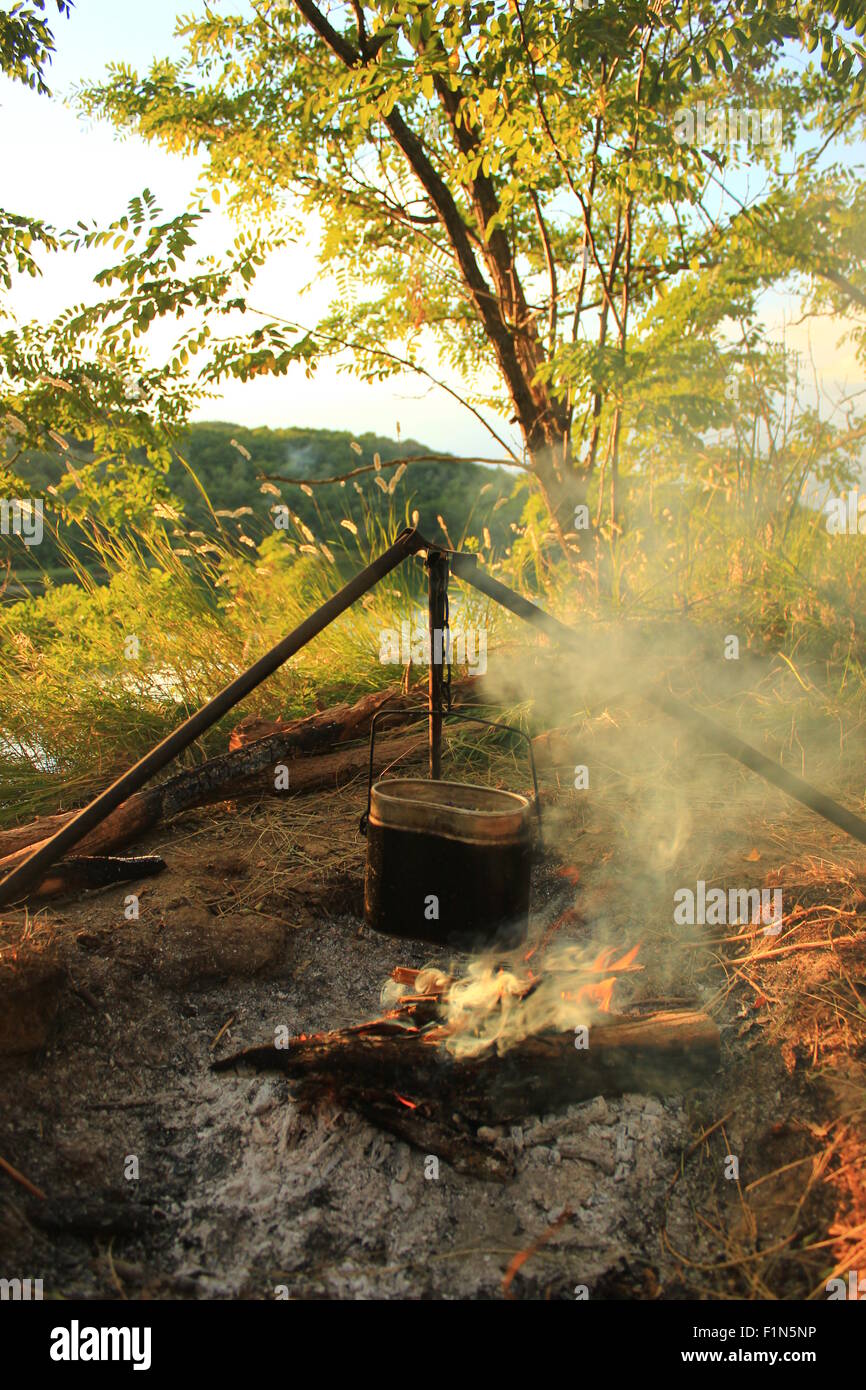La cottura di mangiare in bowler sul fuoco in una escursione. Estate Foto Stock