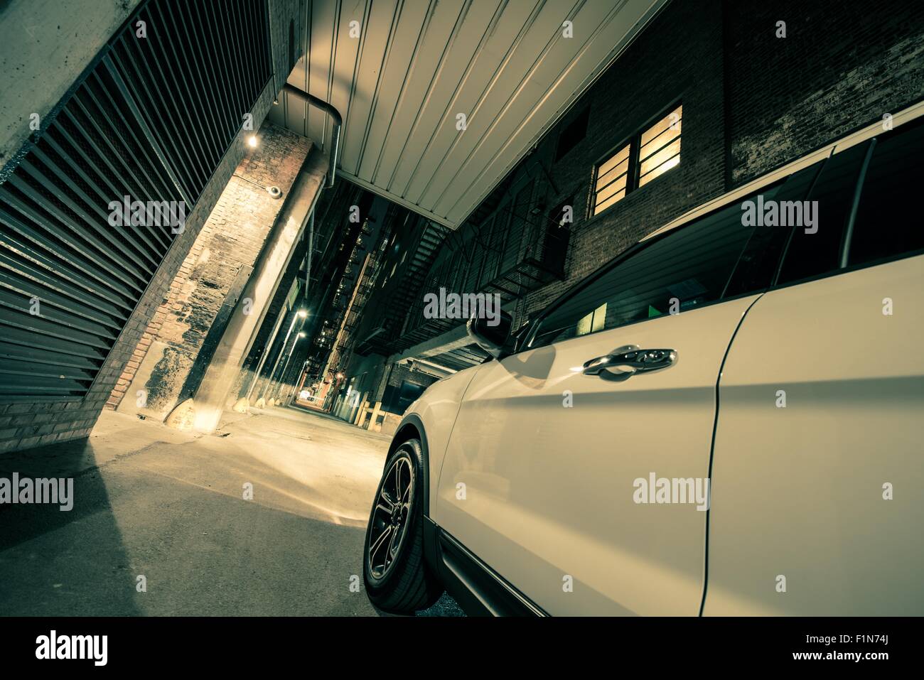 La guida urbana concetto. Bianco Auto SUV sulla città americana Vicolo di notte. Foto Stock