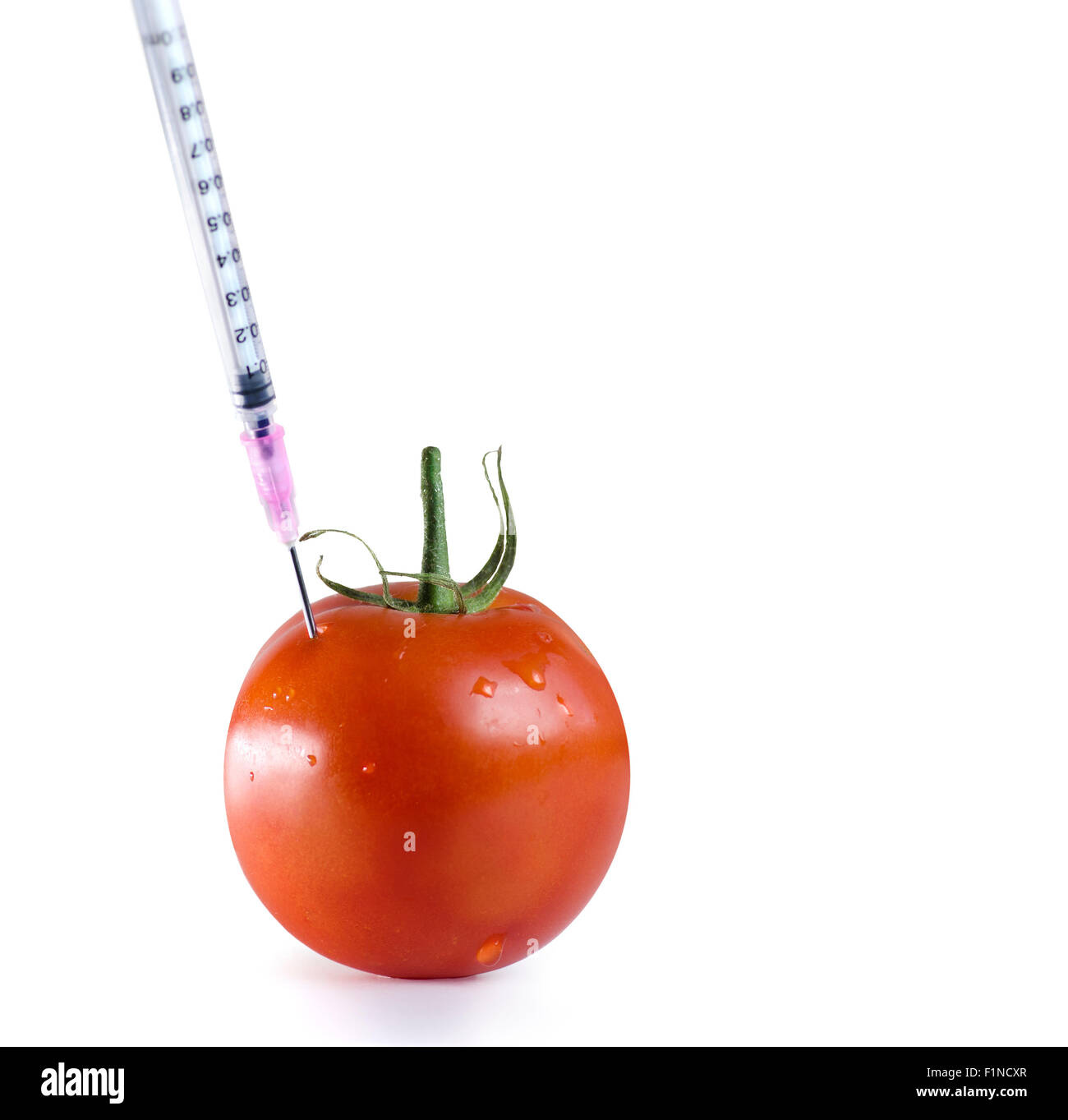 Organismo geneticamente modificato cibo Concetto di immagine. Ago della siringa iniettata all'interno di pomodoro Foto Stock