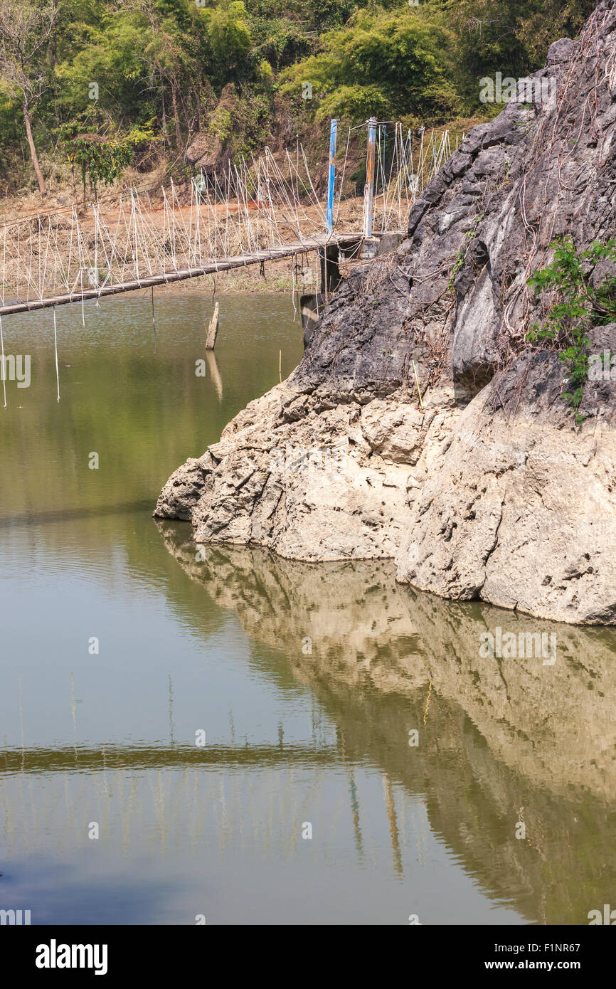 Al di sopra del livello dell'acqua tra due rocce pende un ponte di sospensione Foto Stock