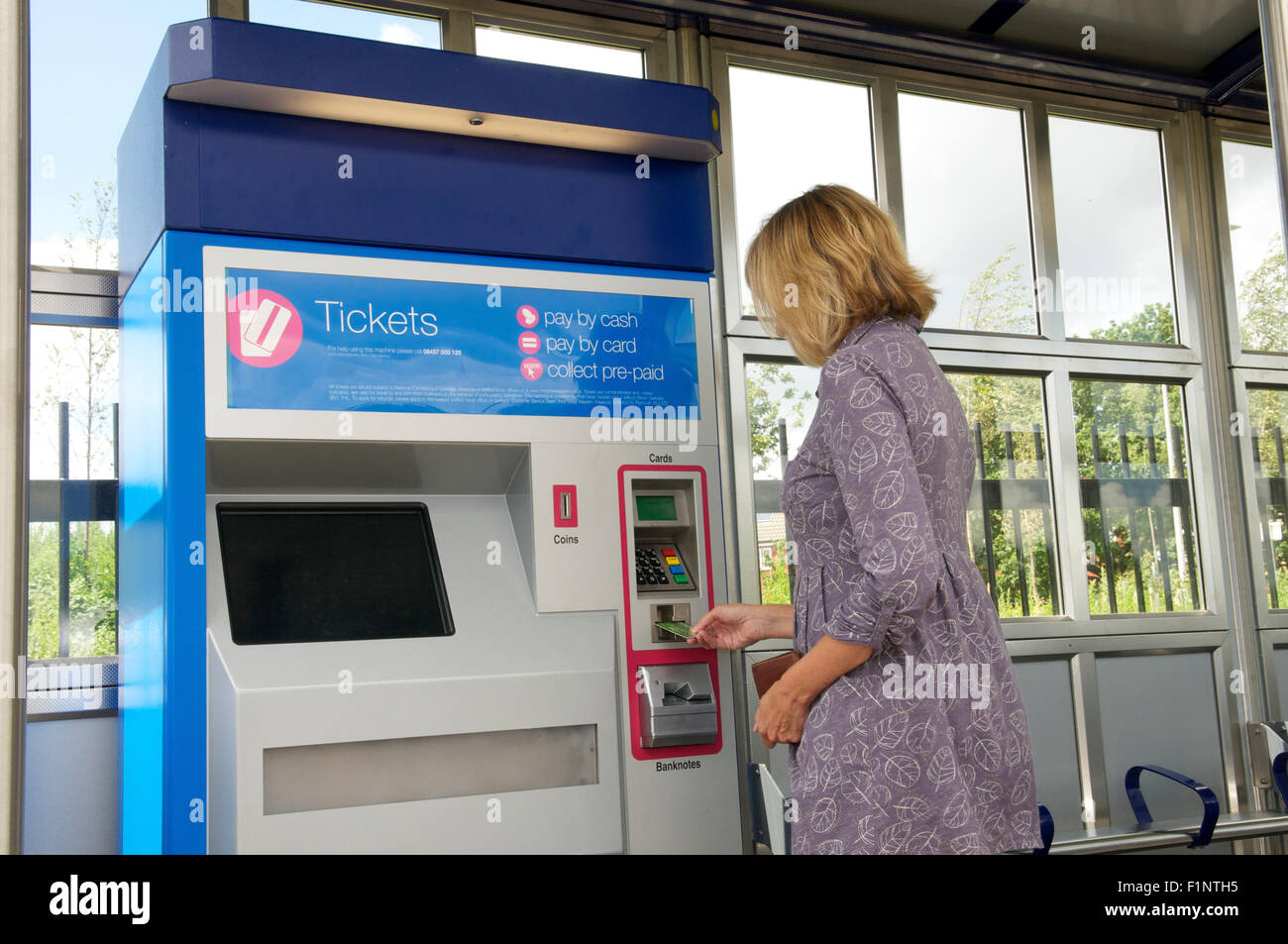 Donna acquisto biglietto ferroviario da un biglietto macchina in corrispondenza di una stazione, REGNO UNITO Foto Stock
