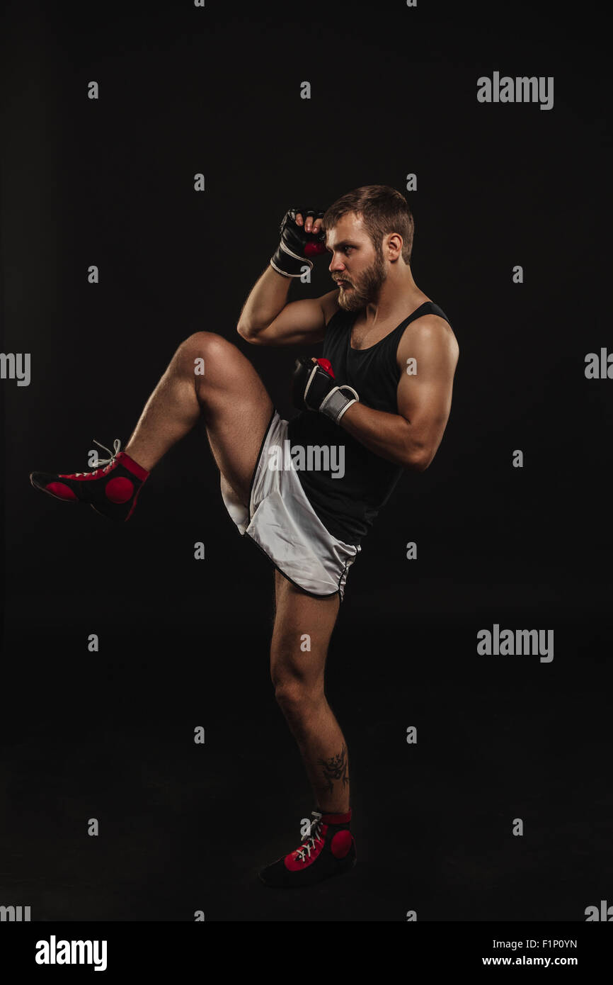 Athletic boxer barbuto con guanti su sfondo scuro Foto Stock