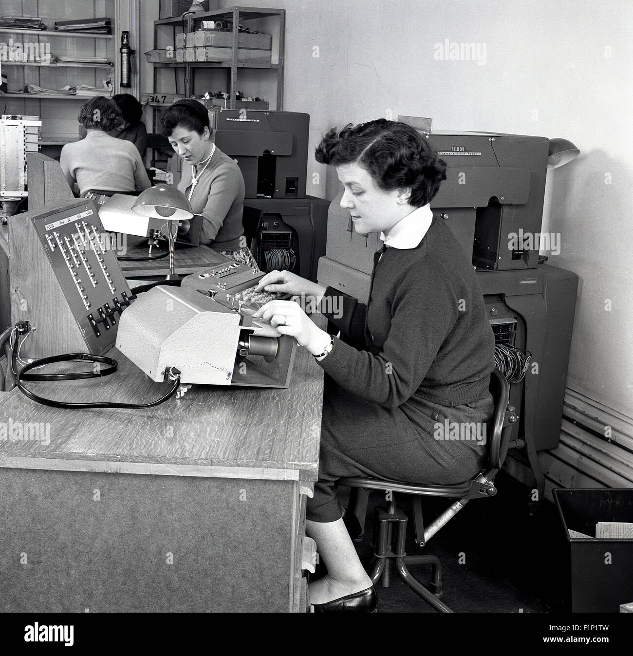 Storico degli anni cinquanta, un'immagine raffigurante un ufficio con segretarie o conti assistenti o gli addetti al lavoro utilizzando varie macchine. Foto Stock
