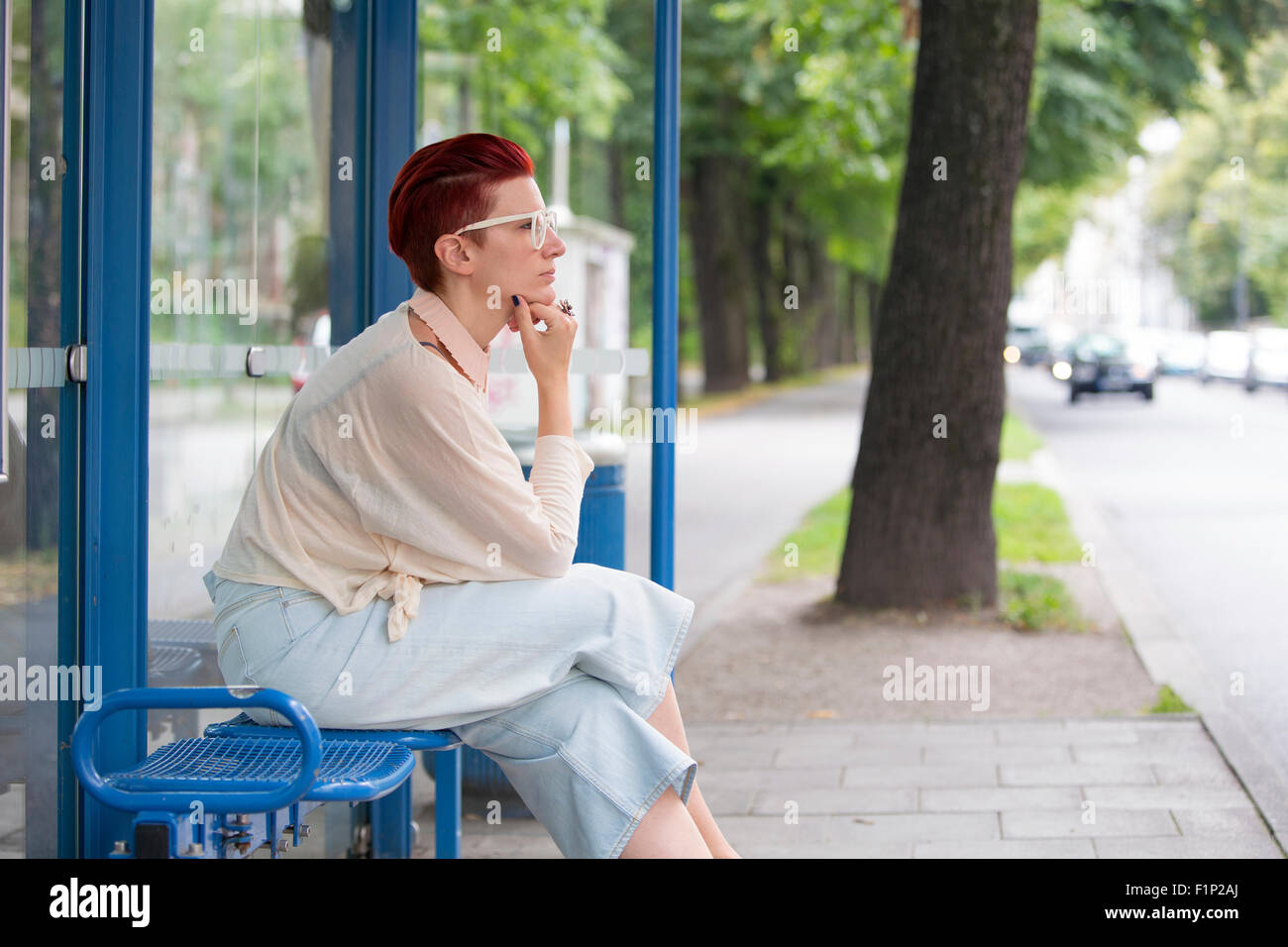 I capelli rossi donna seduta presso la fermata degli autobus e in attesa Foto Stock