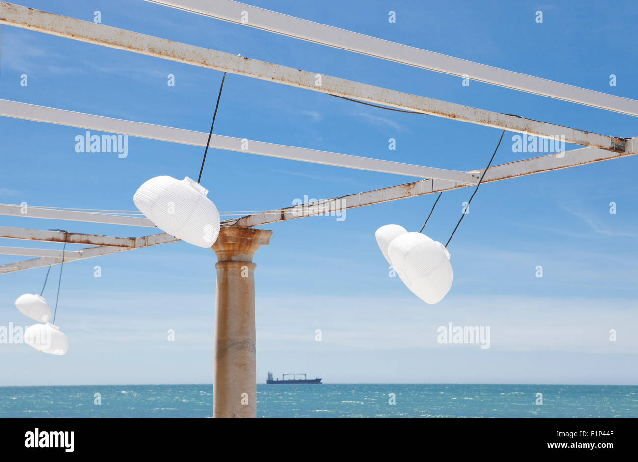 Terrazza accanto al mare con pergola, colonne e lampade di carta una giornata di vento Foto Stock