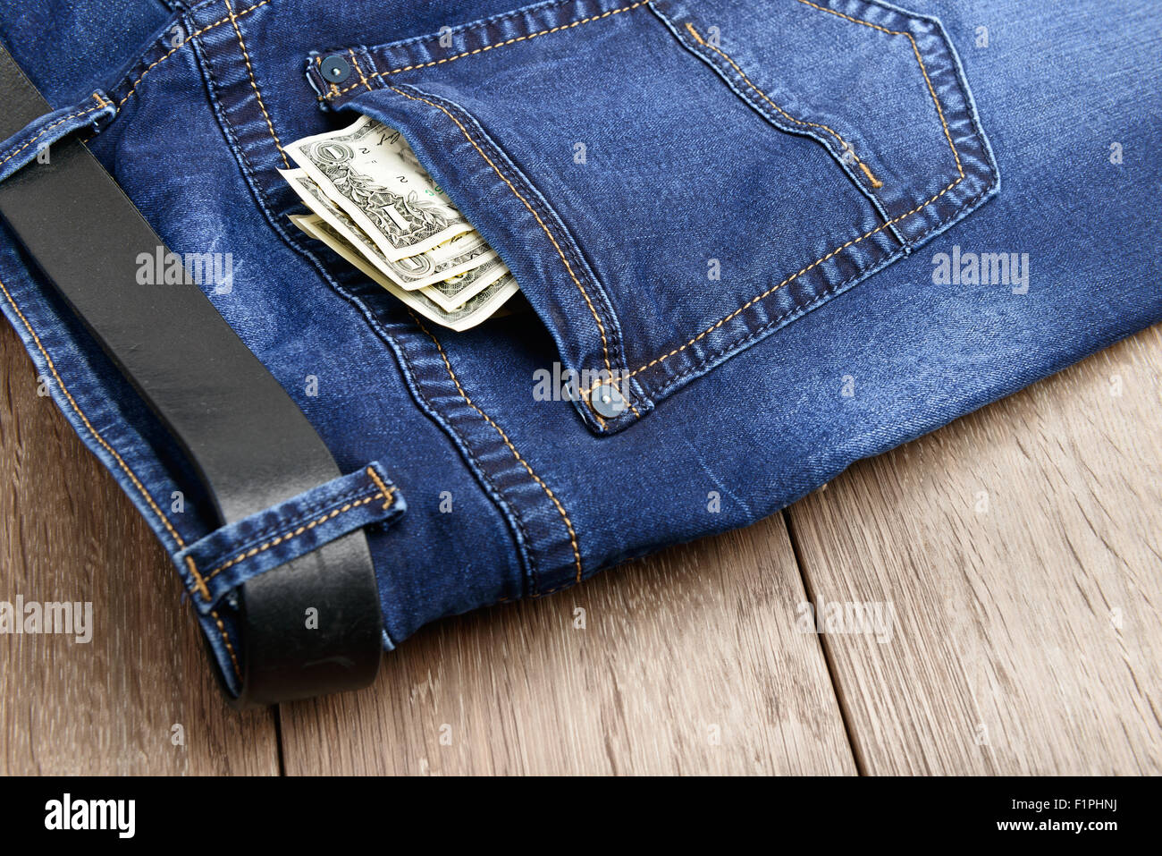 Jeans blu con i soldi in tasca a sfondo di legno Foto Stock