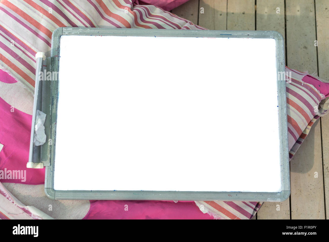 In plastica bianca ardesia con uno spazio vuoto su un cuscino rosa su un pavimento in legno Foto Stock