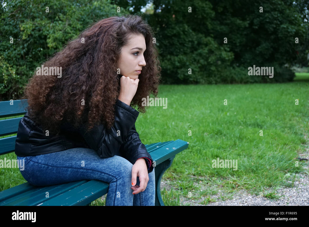 Triste adolescente seduta sul banco di lavoro Foto Stock