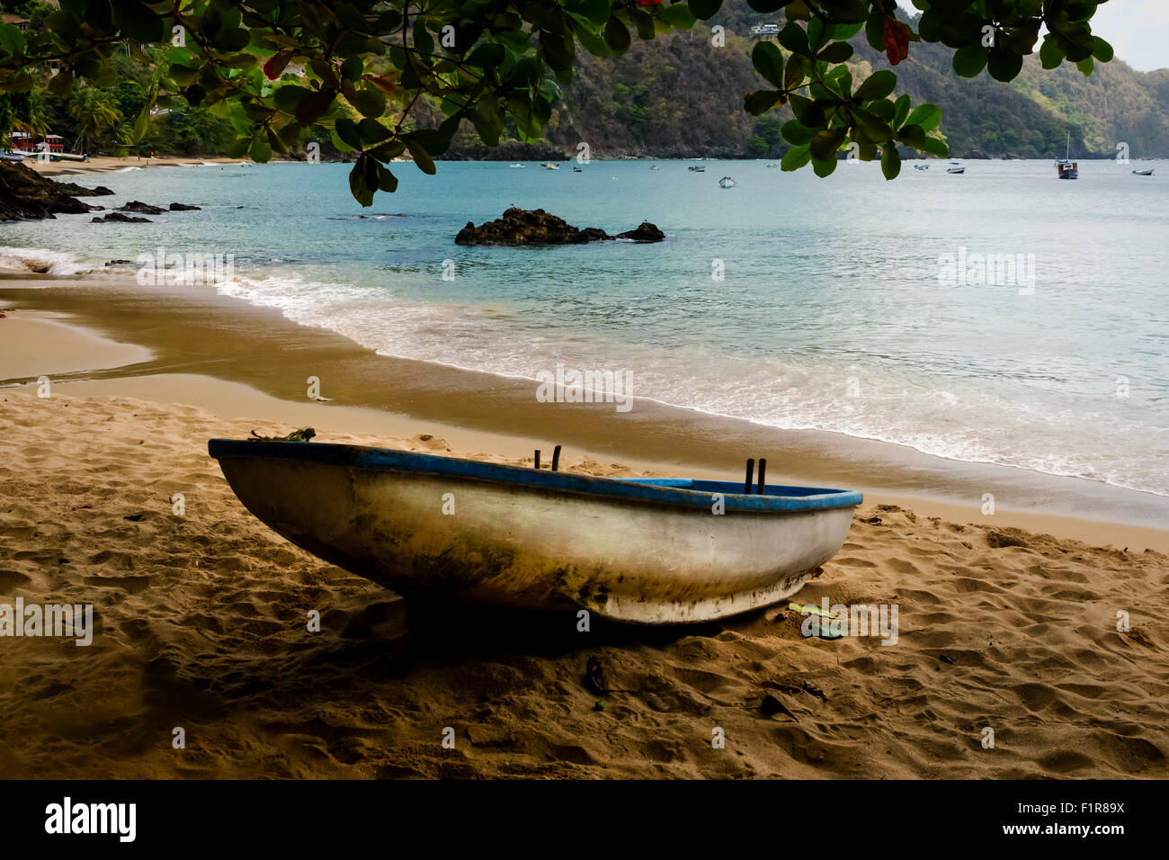 La pesca in barca tirata su holiday resort beach, con bay e rocce in background in un bel po' di castara bay, castara, Tobago Foto Stock La pesca in barca tirata su holiday resort beach, con bay e rocce in background in un bel po' di castara bay, castara, Tobago Foto Stock