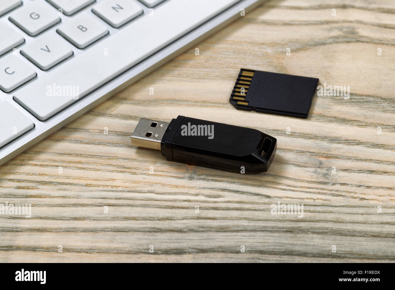 Close up di dati thumb drive e memoria flash card. Tastiera per computer in background sul desktop. Foto Stock