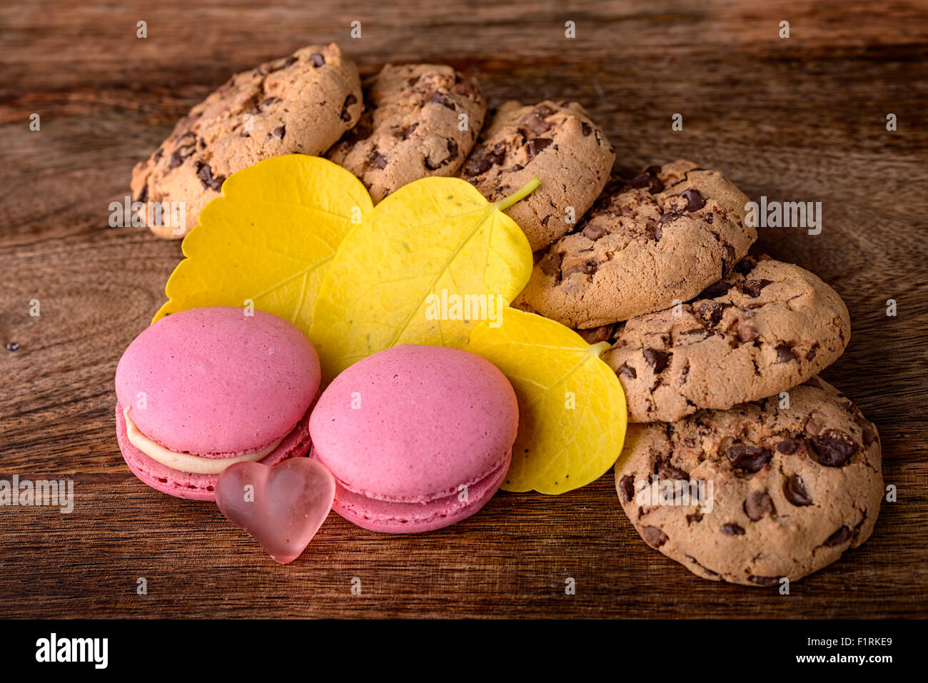 Cookies e rosa macaron con foglie di giallo su legno Foto Stock