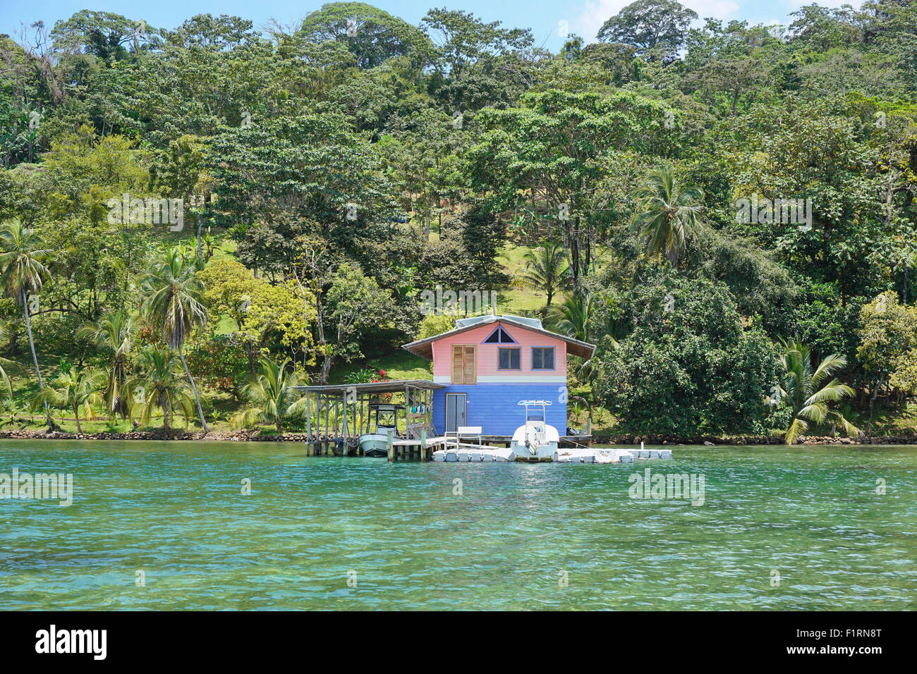 Casa sul mare con imbarcazioni al dock e la lussureggiante vegetazione tropicale sulla Costa Caraibica di Panama, America Centrale Foto Stock