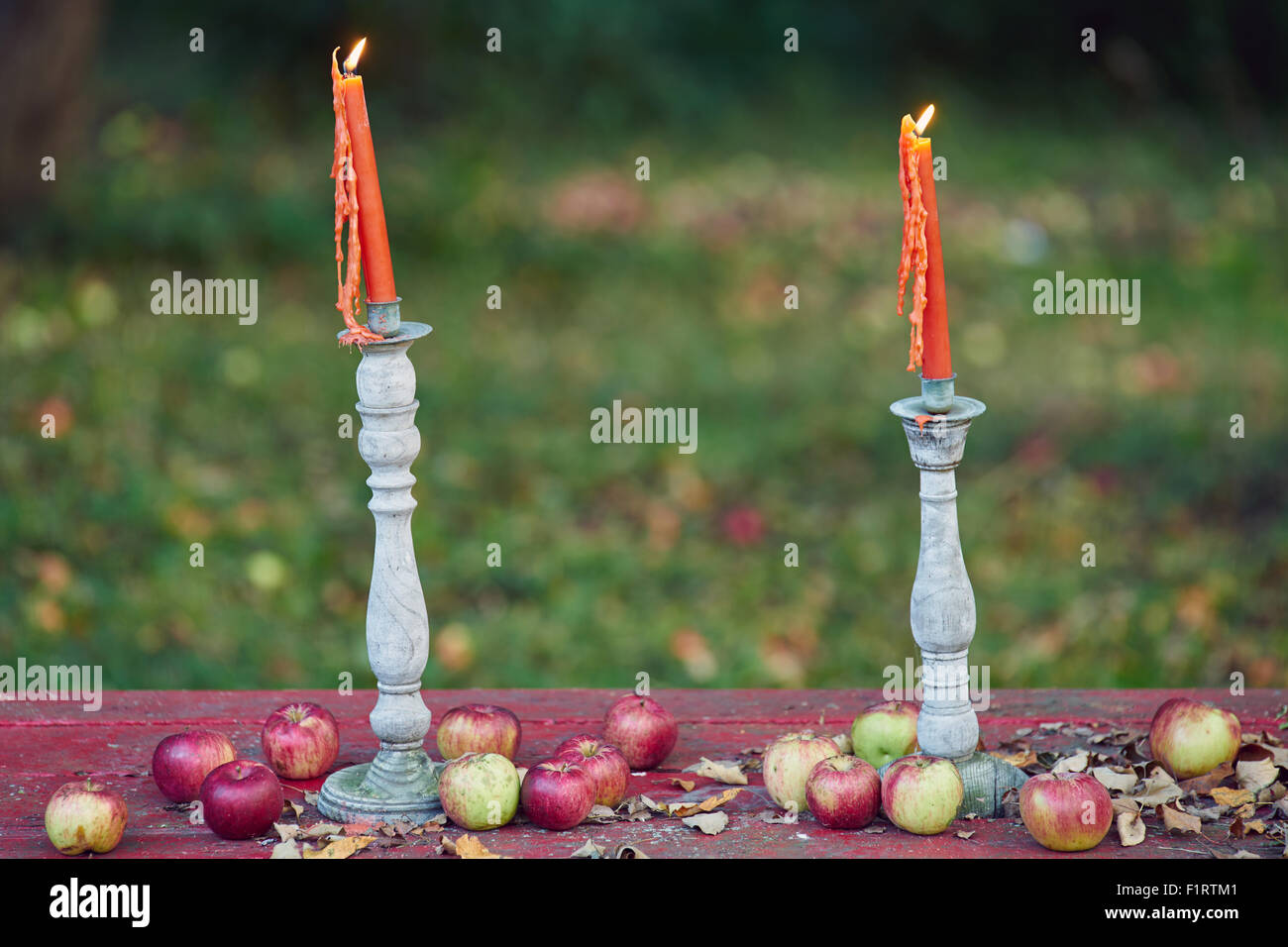 Una coppia di due candele accese su una panchina di mele. Foto Stock