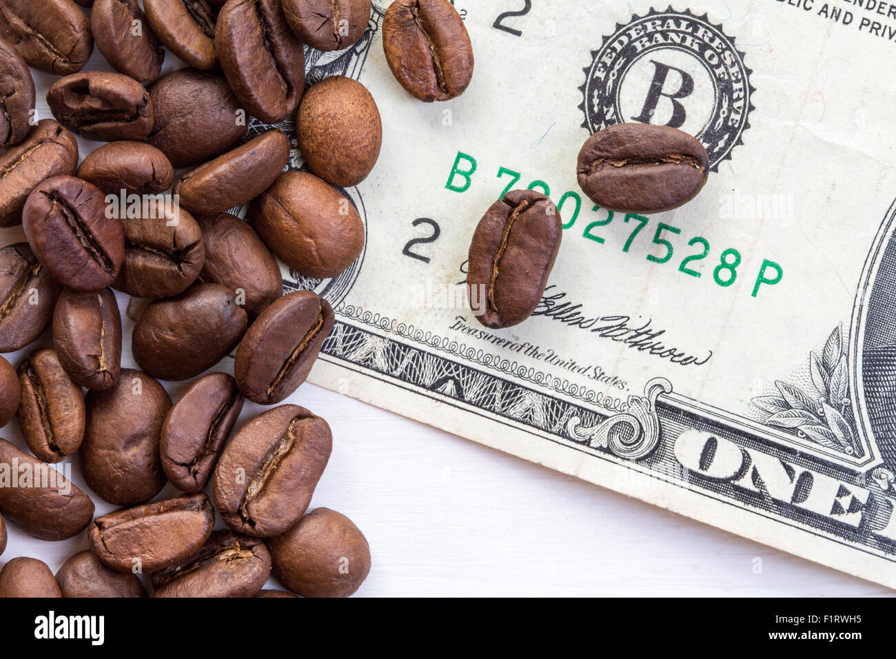 Caffè in grani sparsi sul dollaro. Il concetto del prezzo del caffè sul mercato Foto Stock