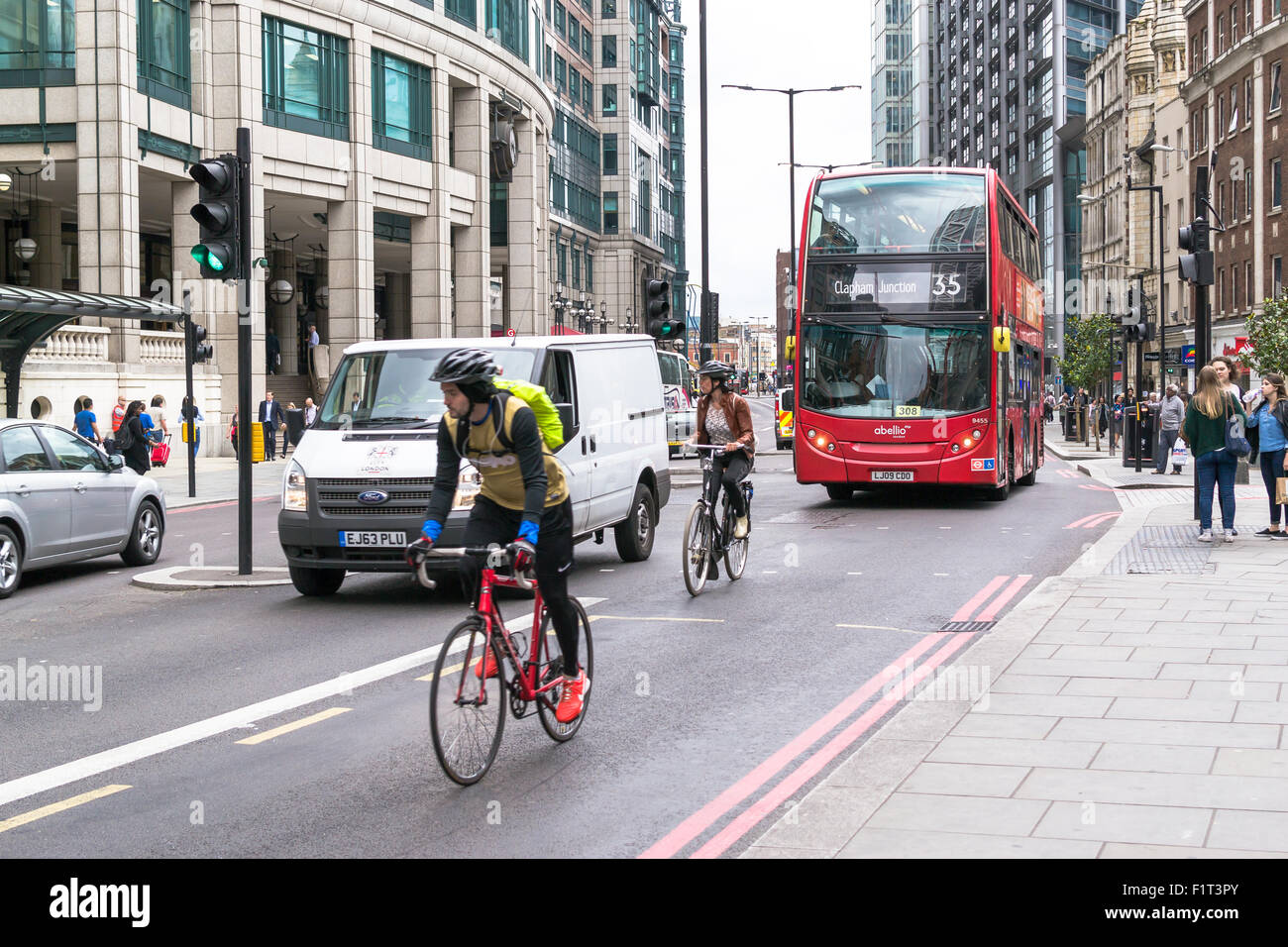 Moderna Red bus e ciclisti urbani in movimento su strade trafficate di Londra Bishopsgate Road durante il periodo estivo di agosto 2015 Foto Stock