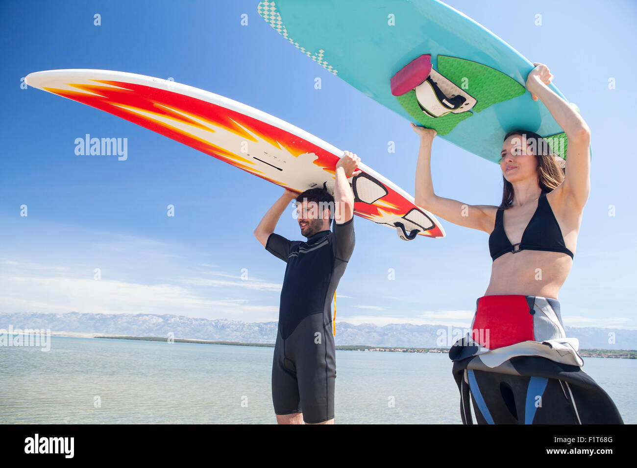 Due surfisti sulla spiaggia che trasportano le tavole da surf sulla testa Foto Stock