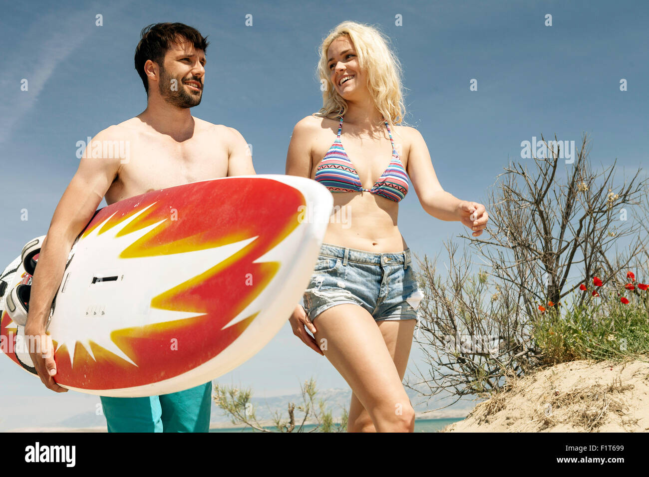 Due persone con la tavola da surf in spiaggia Foto Stock