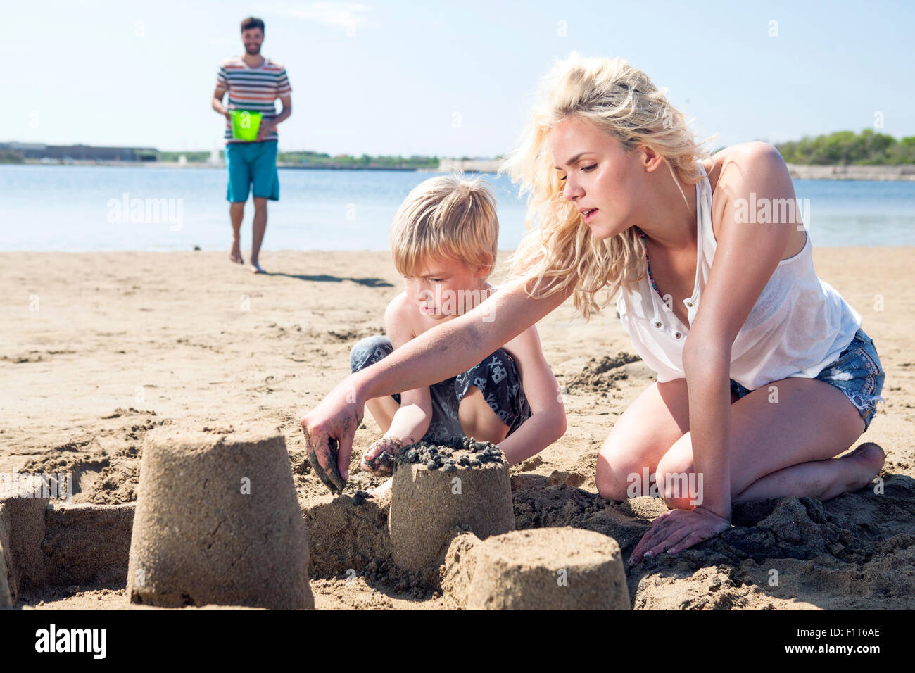 Genitori e figlio facendo sandcastle sulla spiaggia Foto Stock
