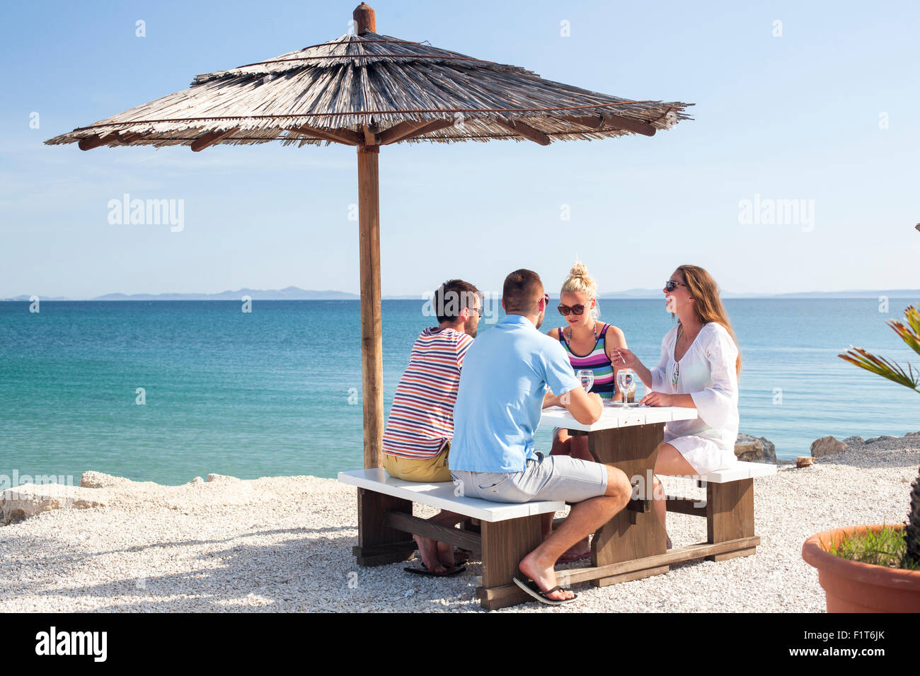Gruppo di amici seduti a tavola nel bar in spiaggia Foto Stock