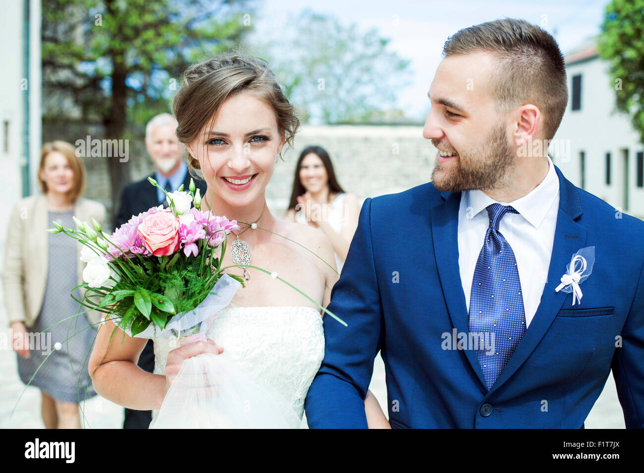 Sposa e lo sposo a camminare con la famiglia in background Foto Stock