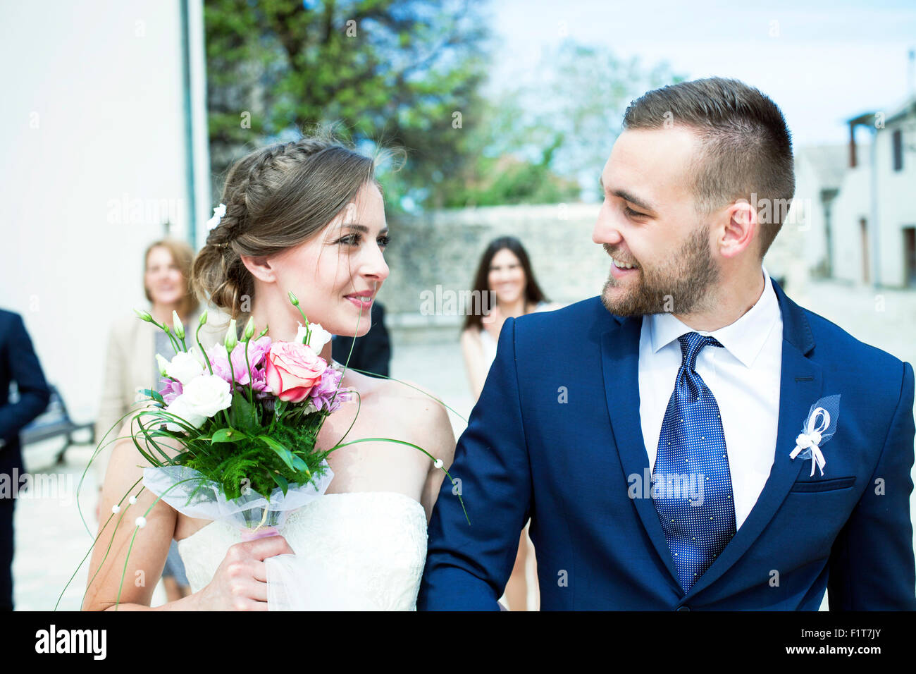 Sposa e lo sposo a piedi con gli ospiti dei matrimoni in background Foto Stock