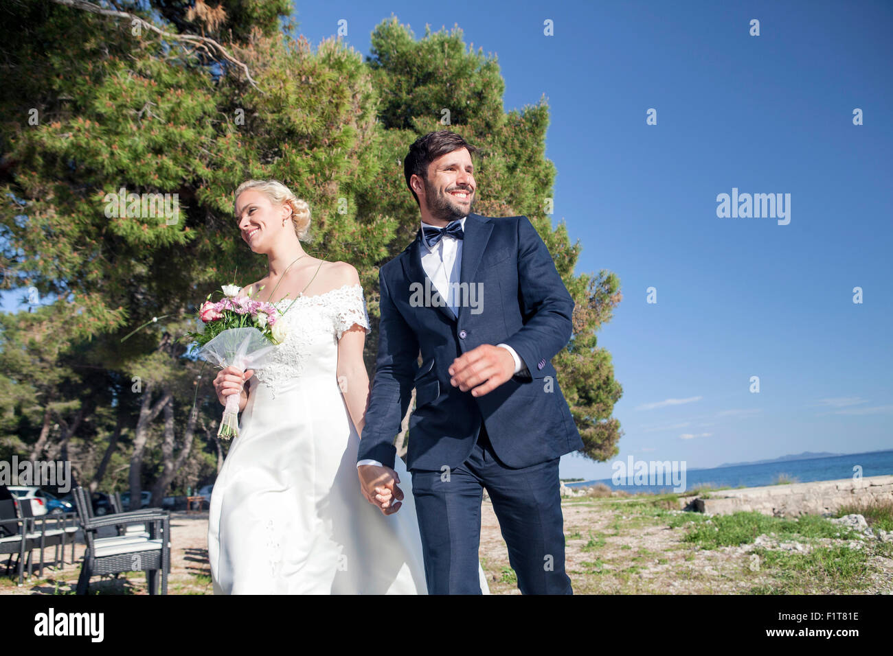 Sposa e lo sposo tenendo le mani all'aperto Foto Stock
