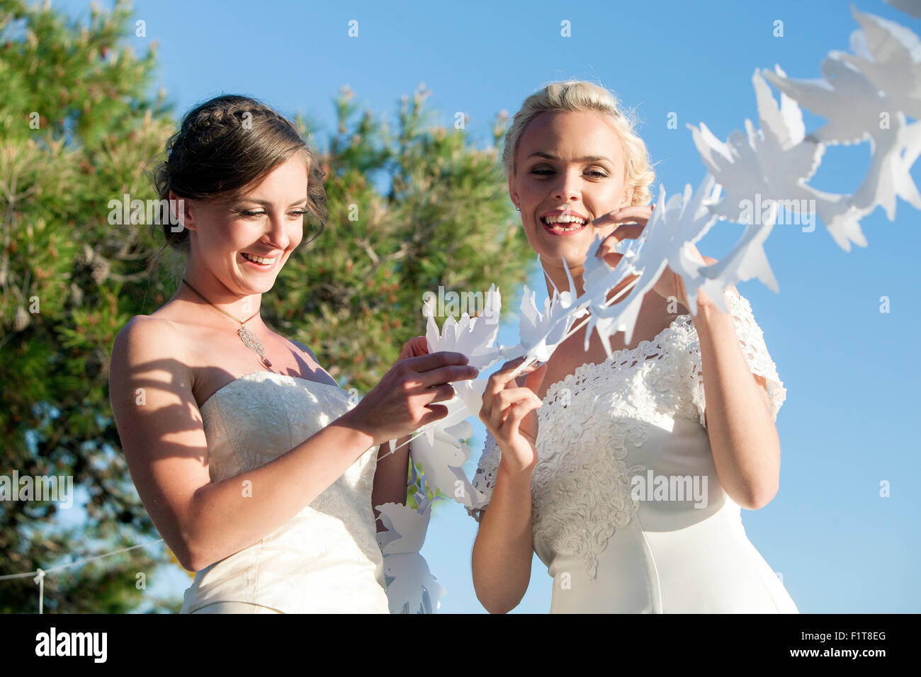 Sposa e damigella giocando con il libro bianco tagliato fuori all'aperto Foto Stock